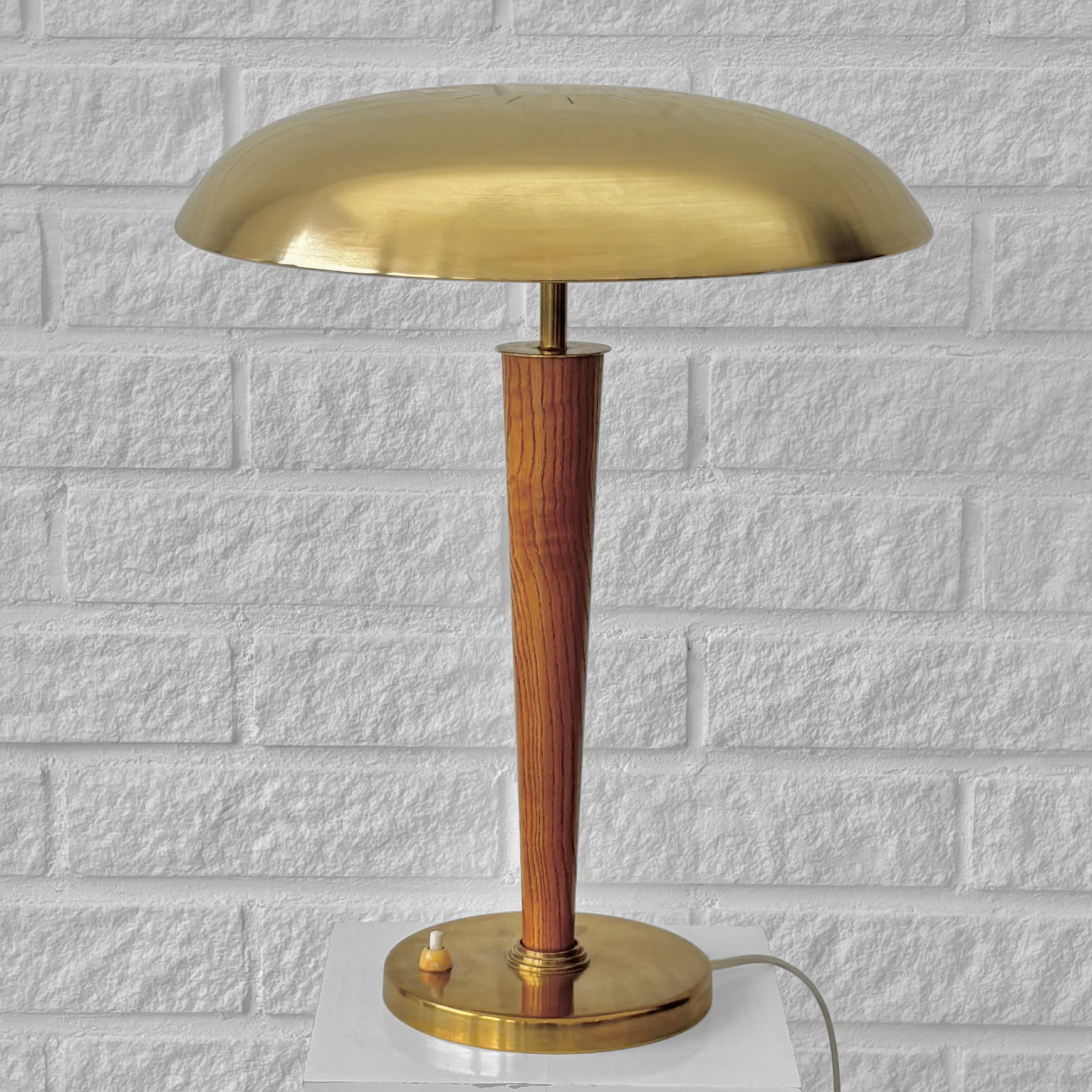 A modernist table lamp, model 8406, produced by the Swedish manufacturer Boréns in the 1940s. Crafted from brass, it features a disc-shaped upper shade supported by a solid elm pillar. The lamp stands on a circular brass base with an integrated