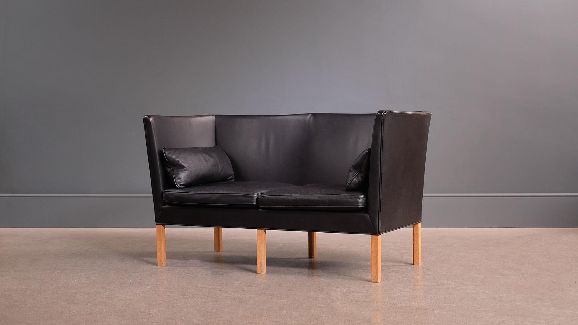 Ultra elegant sofa model 2214 designed by Børge Mogensen for Fredericia, Denmark, 1946. This example with beautifully patinated original black leather, oak legs and original accompanying pillows. Outstanding quality and super comfortable sofa.