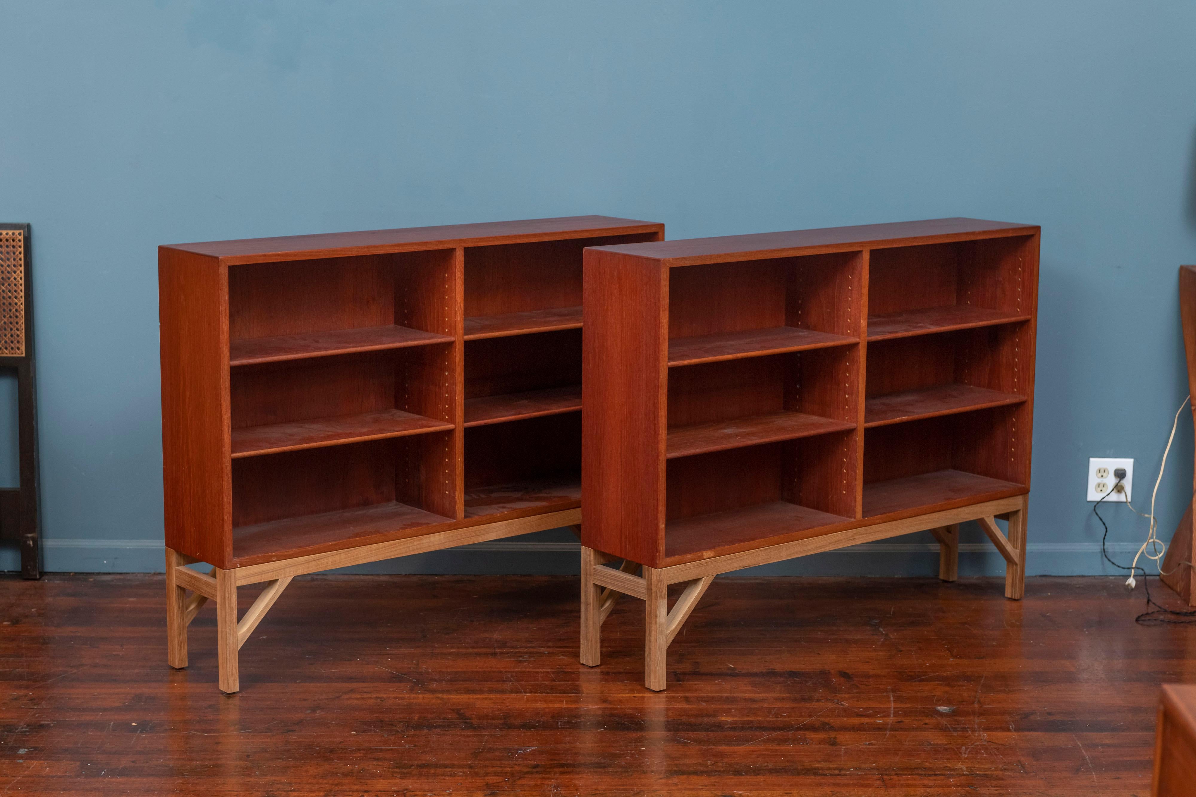 Borge Mogensen design bookcases for C.M. Madsens Fabrikker with Fredericia, Denmark, 1945 / c. 1960. Pair of teak bookcases on oak bases with adjustable shelves, stamped with manufacturers marks to the back.