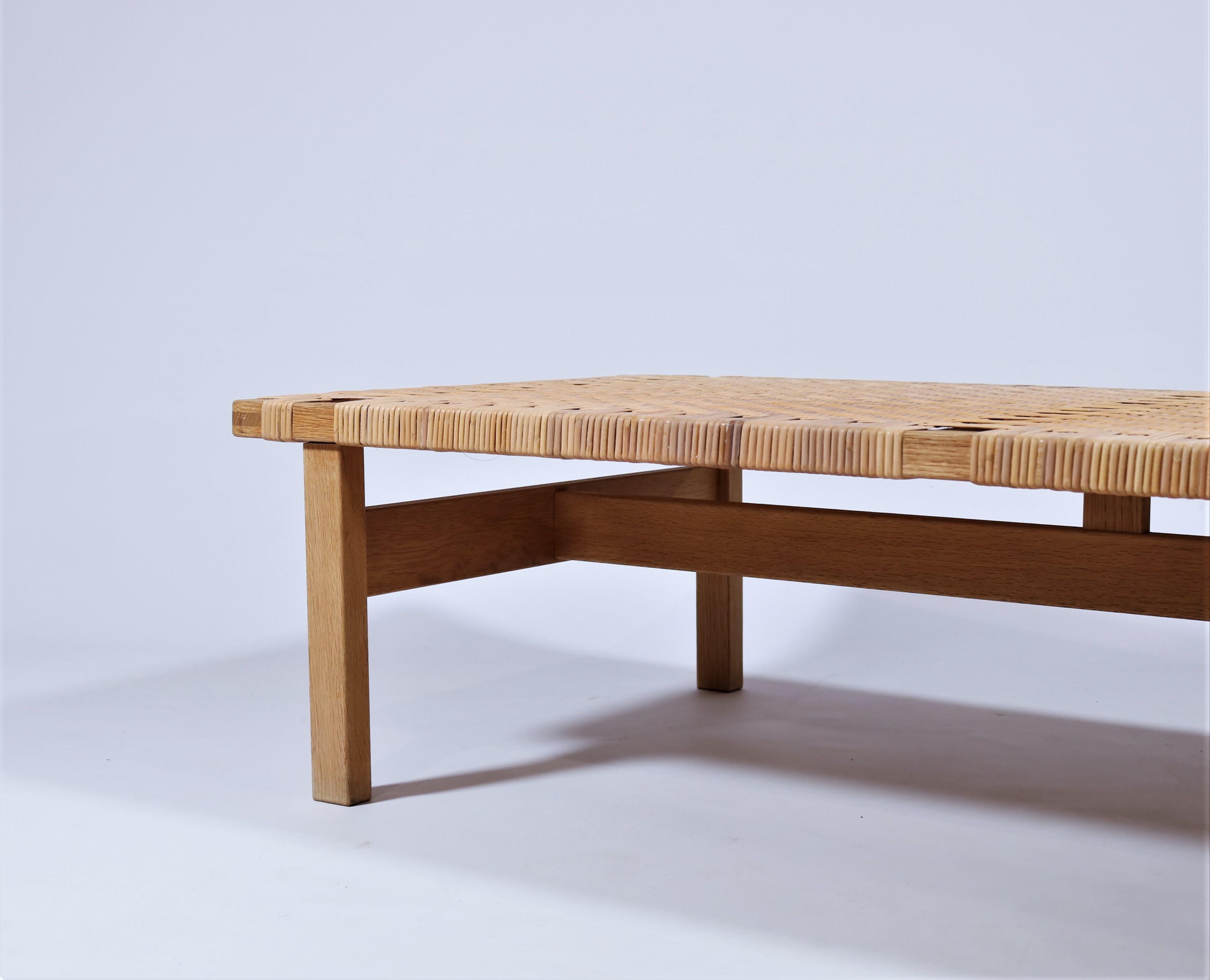 Beautiful bench in solid oak and handwoven rattan cane by Danish architect Borge Mogensen. This piece of furniture is a stunning addition to any interior and can be used both as a low side table and a bench. Mogensen designed the bench in the 1950s