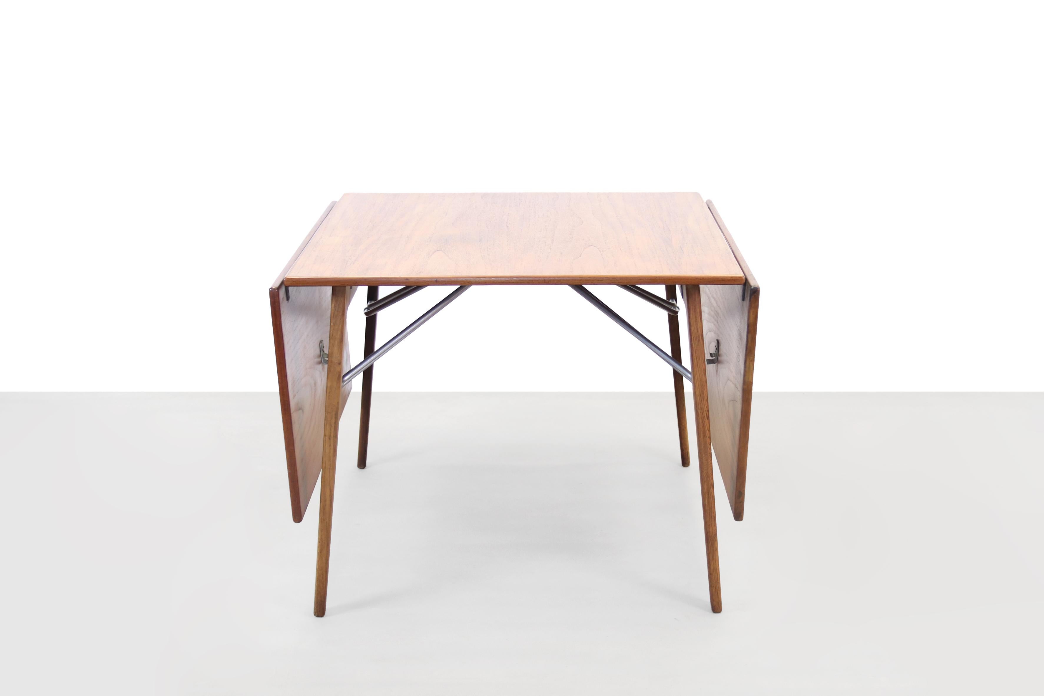 Very special and rare drop leaf dining room table designed by Borge Mogensen from Denmark. This table is made of teak veneered table tops on a solid oak wooden base. Beautiful lines caused by the metal rods that hold up the extra tops, but which can