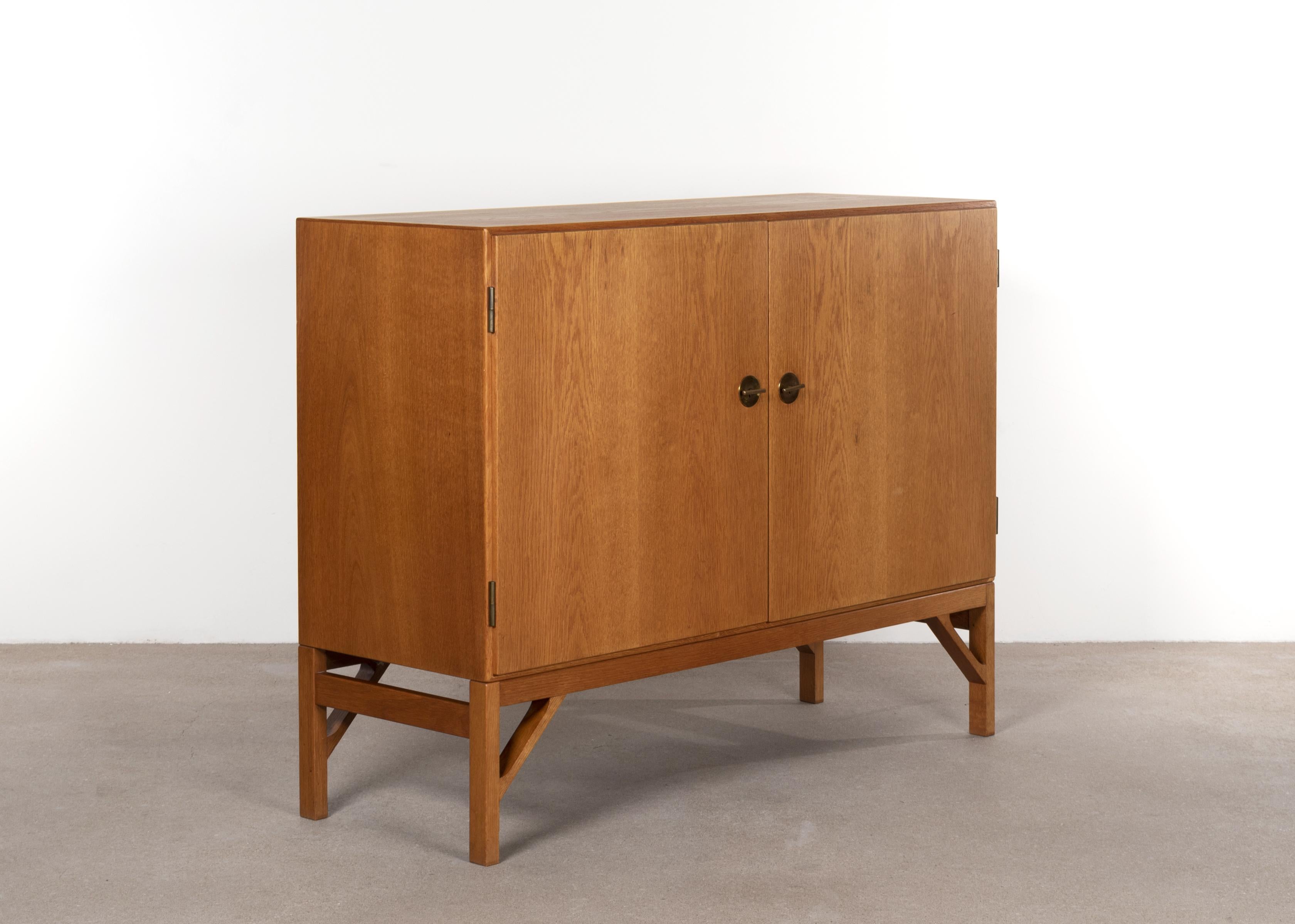 Elegant cabinet by Børge Mogensen model no. 232 designed in 1951. Oak veneer with shallow drawers and shelves in birch and brass details. All in very good condition with minor traces of use.