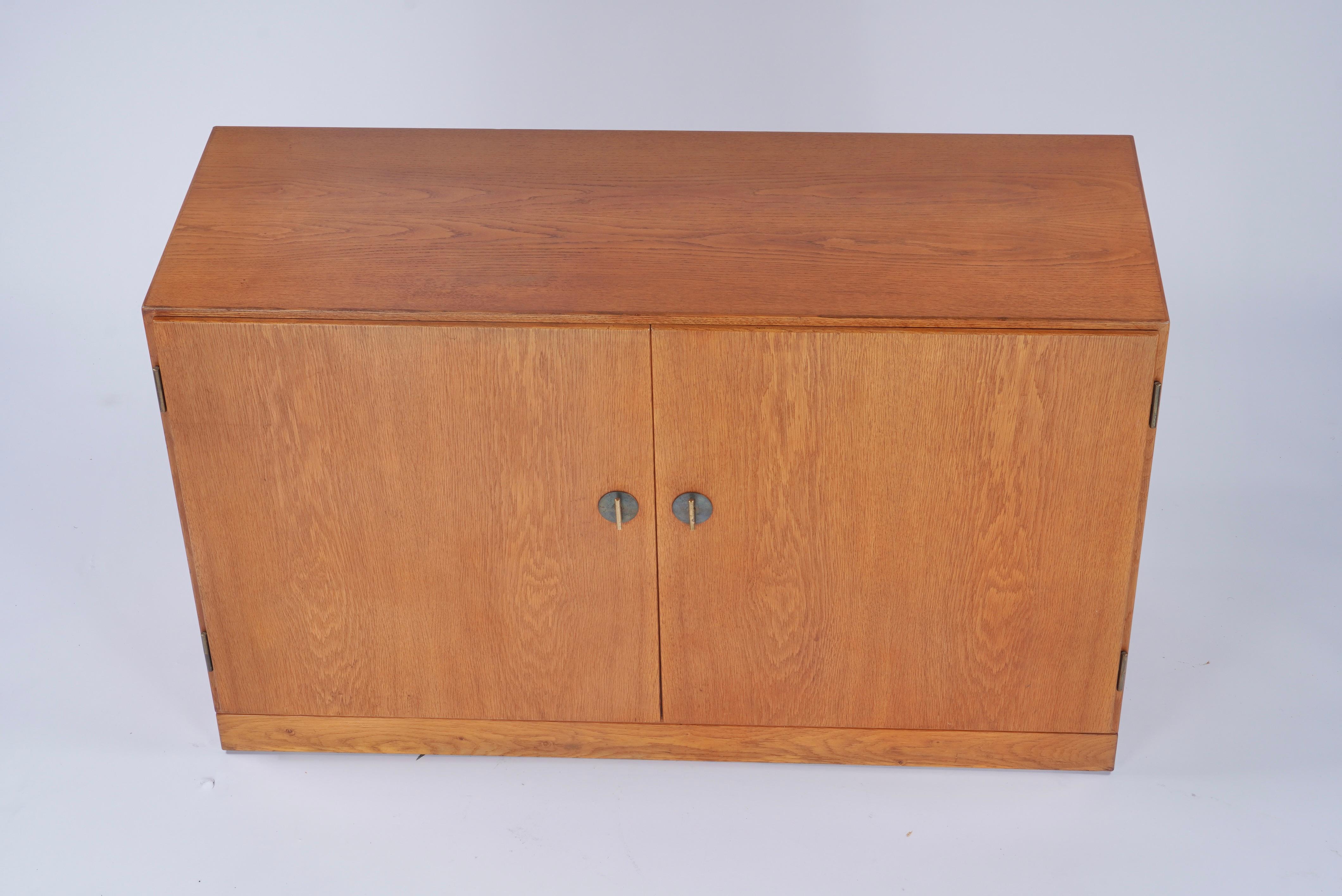 Teak, oak and brass Borge Mogensen for FDB Möbler of Denmark model 232 sideboard with pull out drawers and shelves. Having four shallow drawers and two pull out shelves. The sleek door pulls are incorporated into the locking mechanism and are a