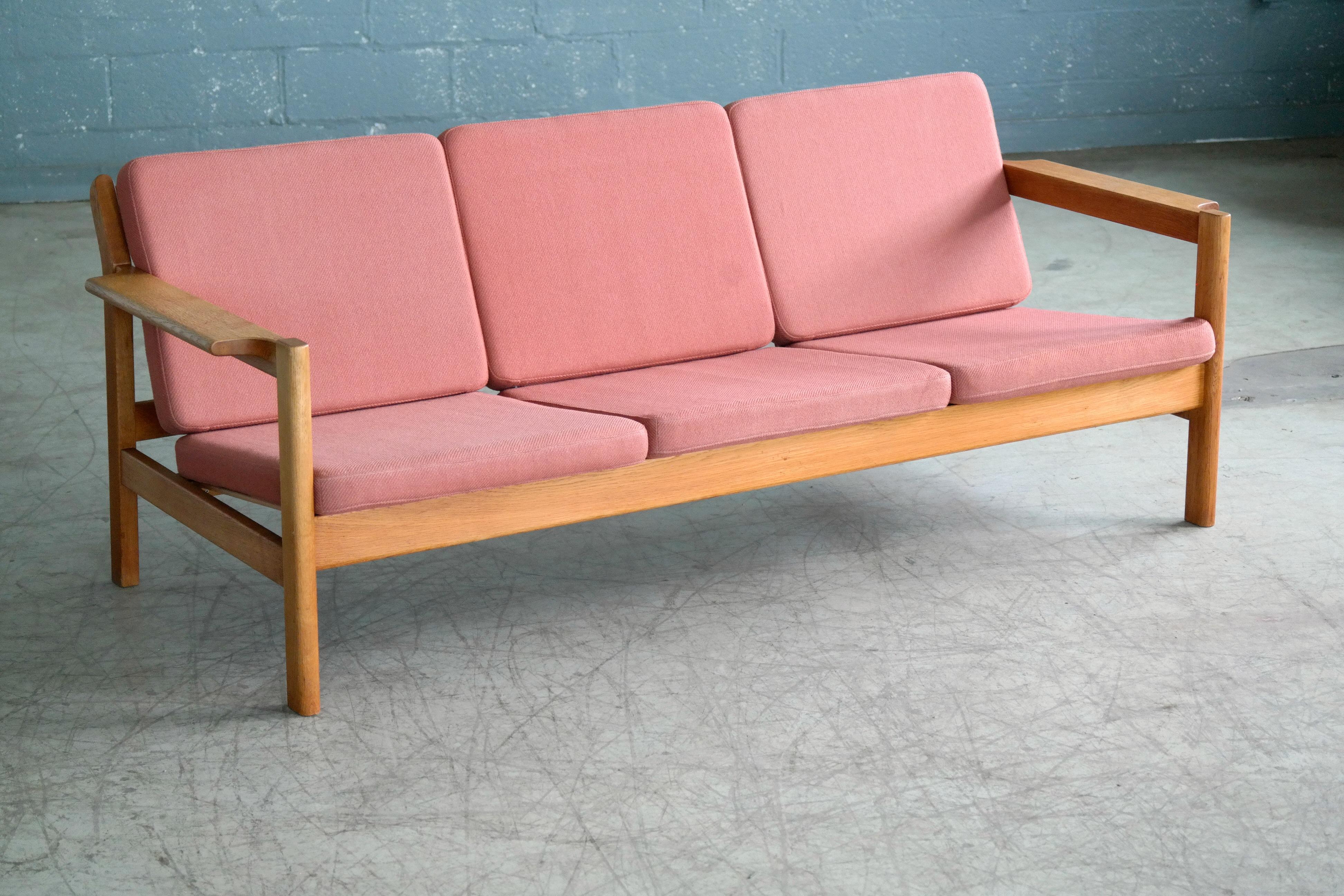 Classic Danish design by iconic Designer Borge Mogensen - designed in the 1960s and made from solid oak by Fredericia (labeled on the frame). 
We love the elegant angles of the sofa combined the slim cushions still covered in their original pale