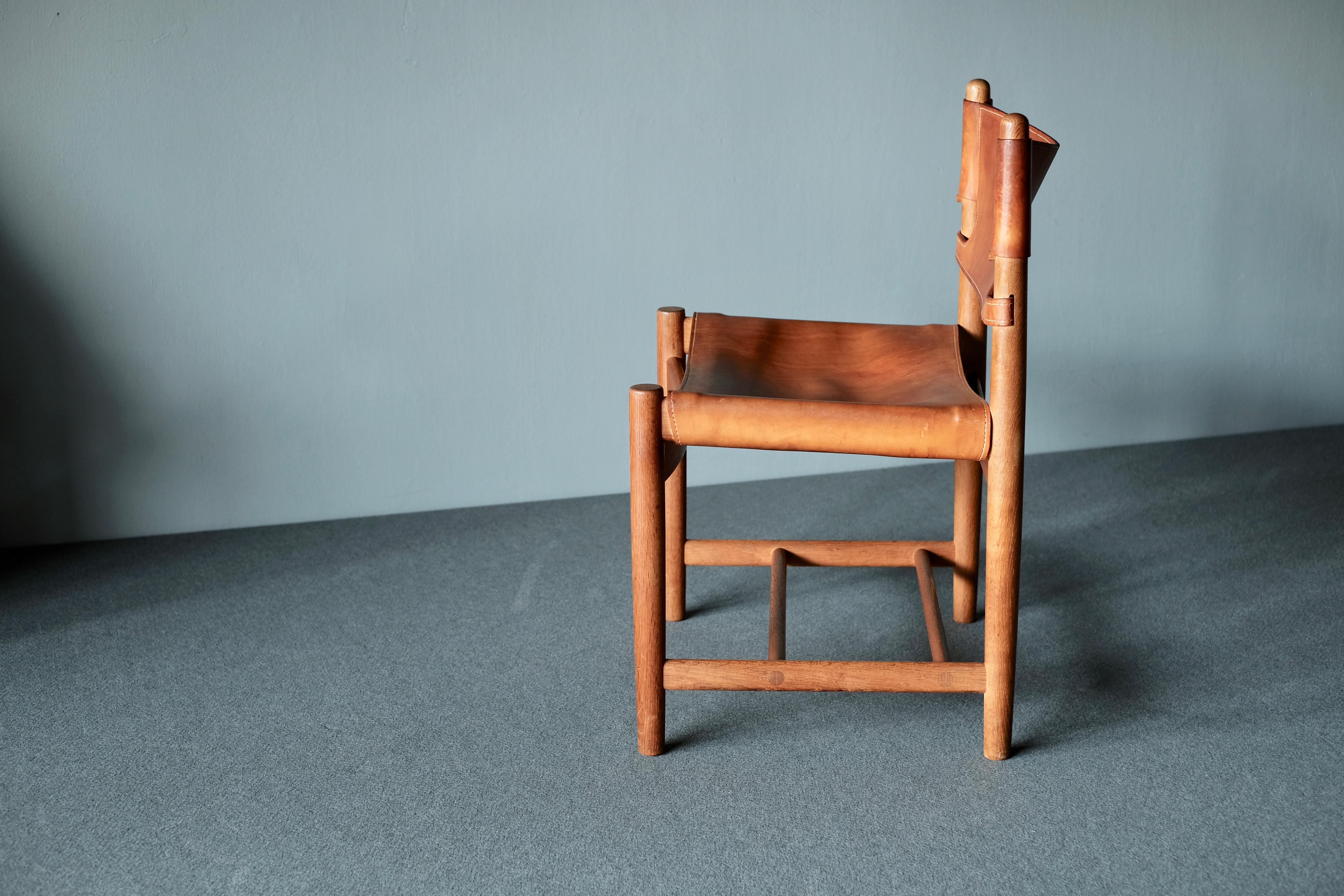 Chair by Borge Mogensen, manufactured by Fredericia. It has a solid oak frame and saddle leather seat and backrest. In order to give more comfortable back support the leather at the top of the backrest is cut so it curves slightly at the top. The