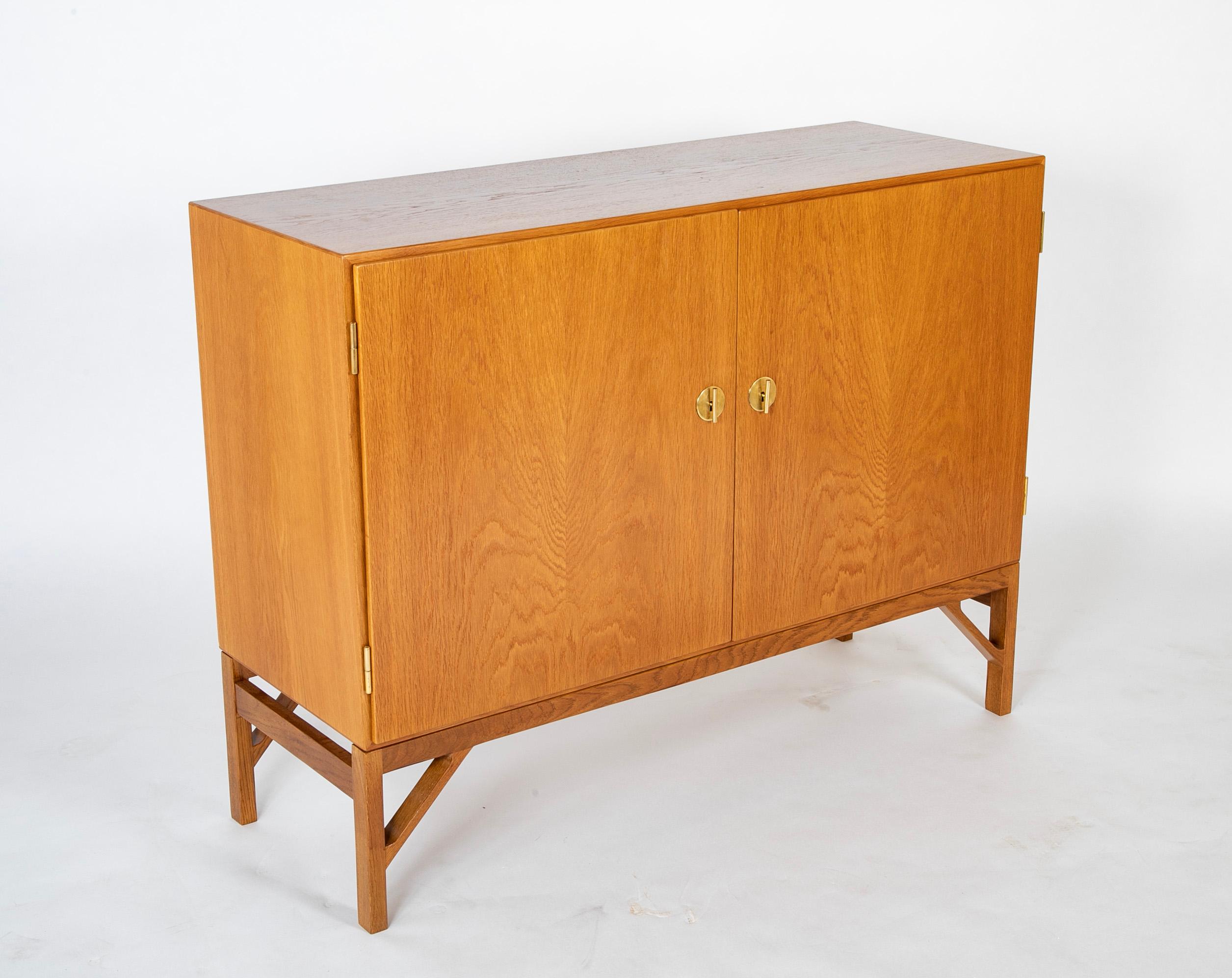 Oak cabinet, model 232, also known as 'China' cabinet, designed by Børge Mogensen and produced by FDB in Denmark.  Front with two doors and brass keys that also serve as handles. Inside with shelves and pullout trays. Manufactured and marked by C.M.