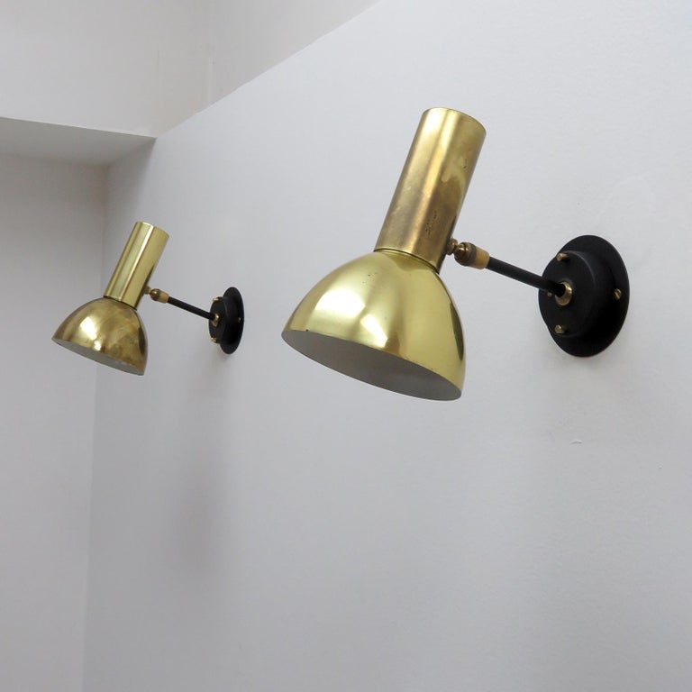 Elegant brass bodied adjustable sconce, swivel joint at the cylinder, ball joint at the back plate, circle of perforations at top of cylinder, with detachable shade extensions & custom back plate. Wired for US standards, one E27 socket per fixture,