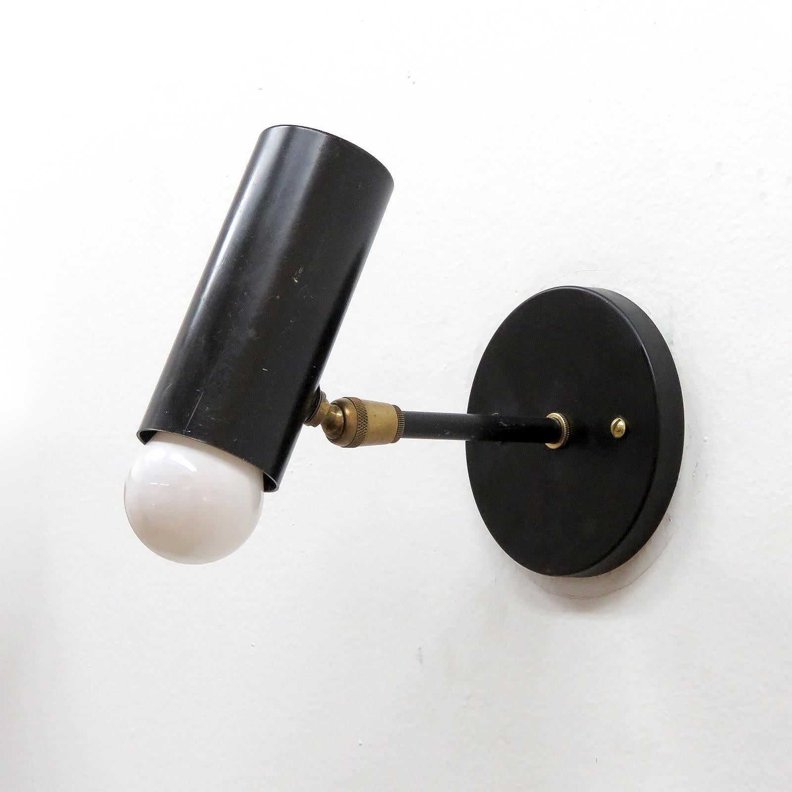 Eleganti lampade da parete articolate, in metallo smaltato nero con accenti in ottone, snodo girevole sul cilindro, estensioni del paralume complementari staccabili (non mostrate) e piastra posteriore personalizzata USA. Cablata per gli standard