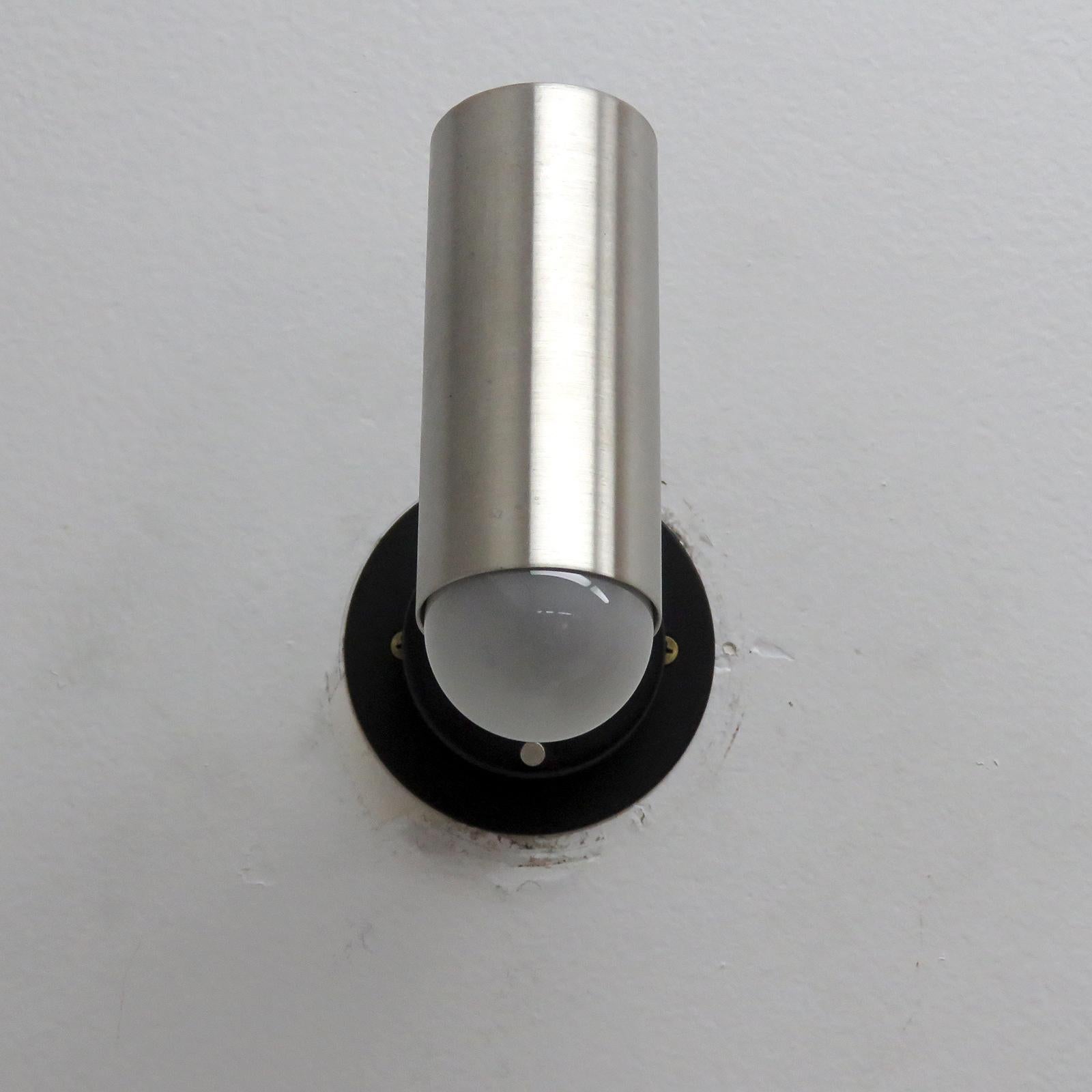 Pair of elegant articulate wall lights by Jean Boris Lacroix, France in brushed aluminum and enameled metal, swivel joint at the cylinder, ball joint at the back plate, circle of perforations at top of cylinder, shade extension available, custom