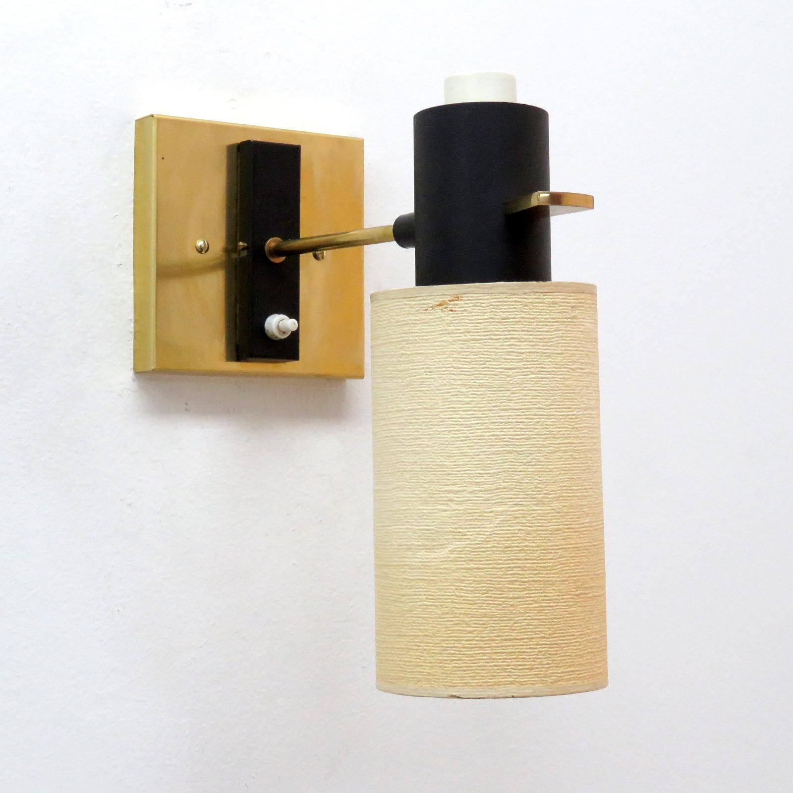 Elegant pair of French articulate wall lights brass by Boris Lacroix with original paper shades on a black enameled body with brass detailing, a signature brass handle to adjust the sconces and on/off switch on the original black back plate, custom