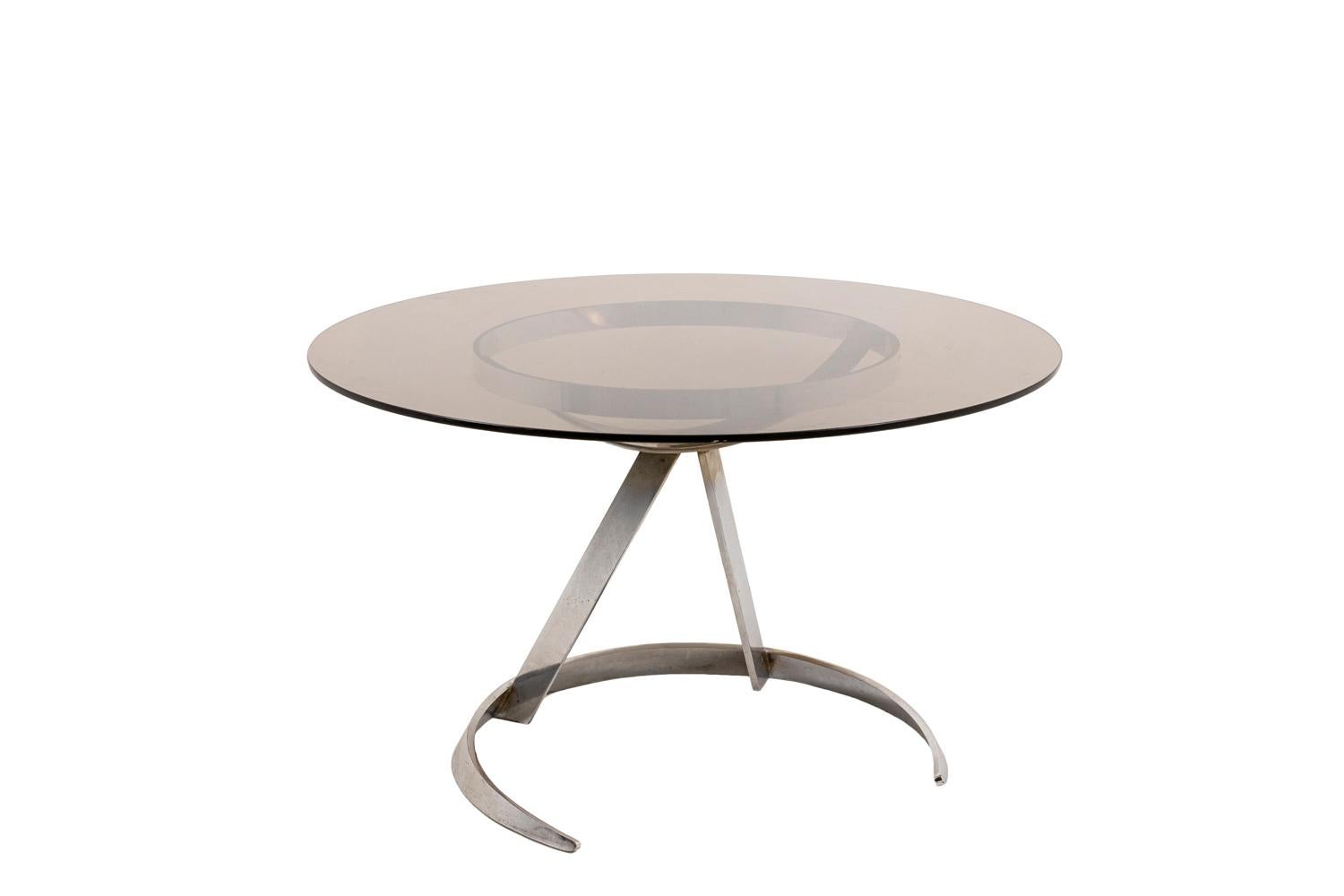 Boris Tabacoff, attributed to. 

Round table in chromed metal and smoked glass. The base is formed by a semi-circular base and a circular support on which the glass top is placed.

Work realized in the 1970s.
 