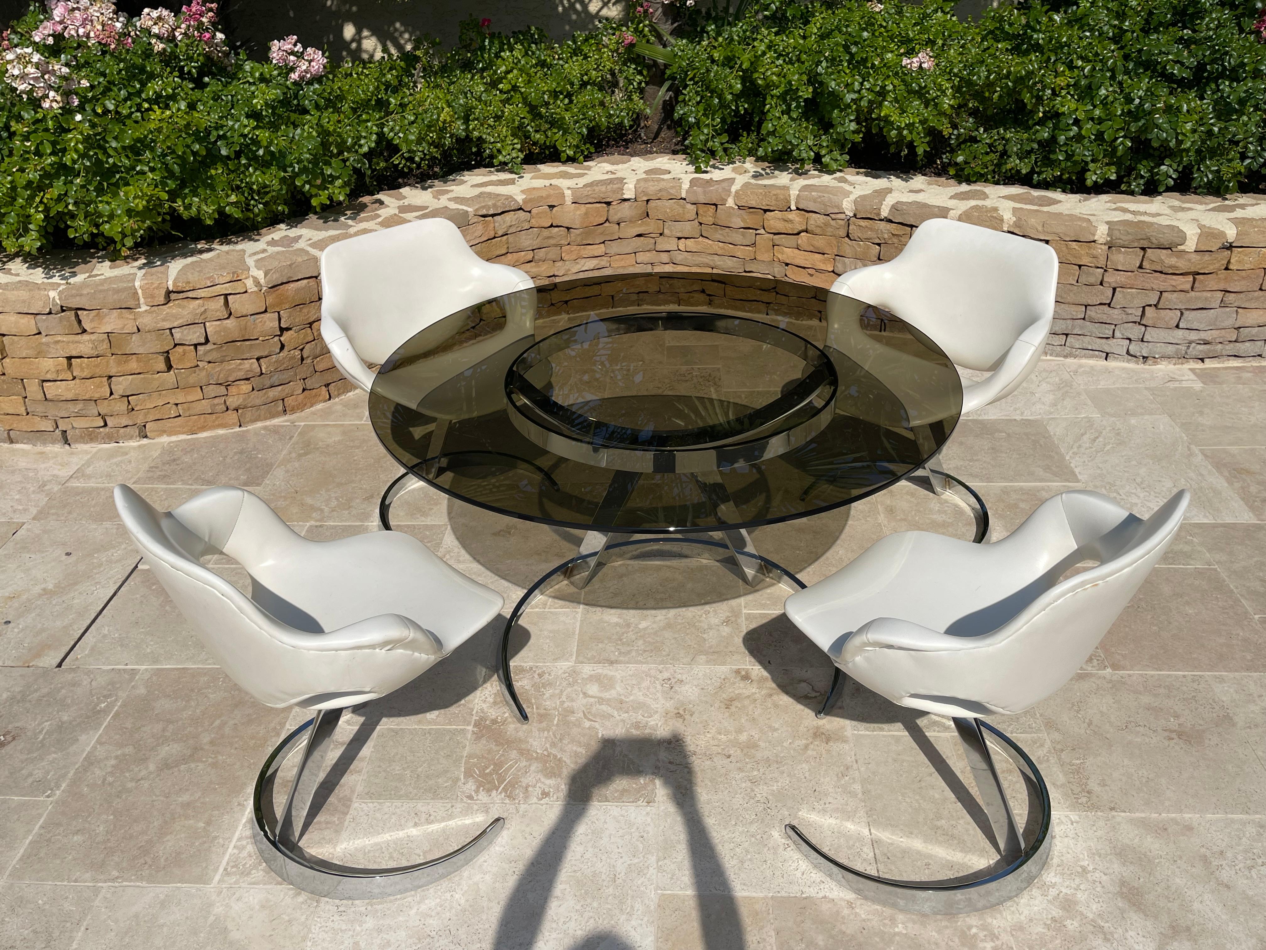 Ensemble de salle à manger design par Boris TABACOFF composé d'une table ronde avec base en acier inoxydable et plateau en verre fumé et de 4 chaises. Très bel ensemble en très bon état.

Dimensions
- Table : Diamètre du plateau 1m20 x Hauteur 71cm