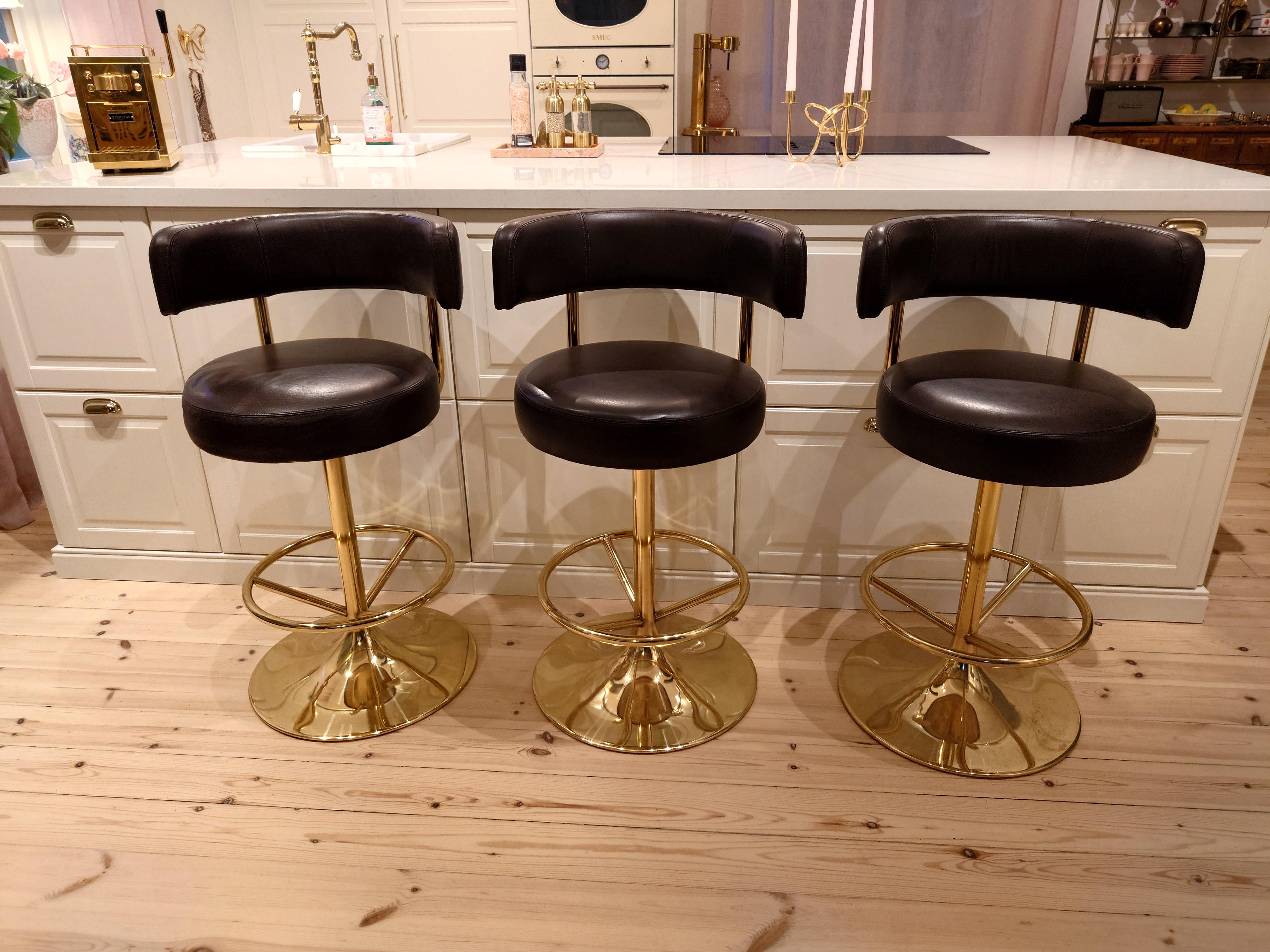 Börje Johanson for Johansons Design,set of  three Barstools as part of Johanson Jupiter Collection', metal, Leatherette,Sweden 1970s. Swivel chairs on pillar bases in gold-coloured metal. Padded back and seat with dark brown upholstery. One chair is