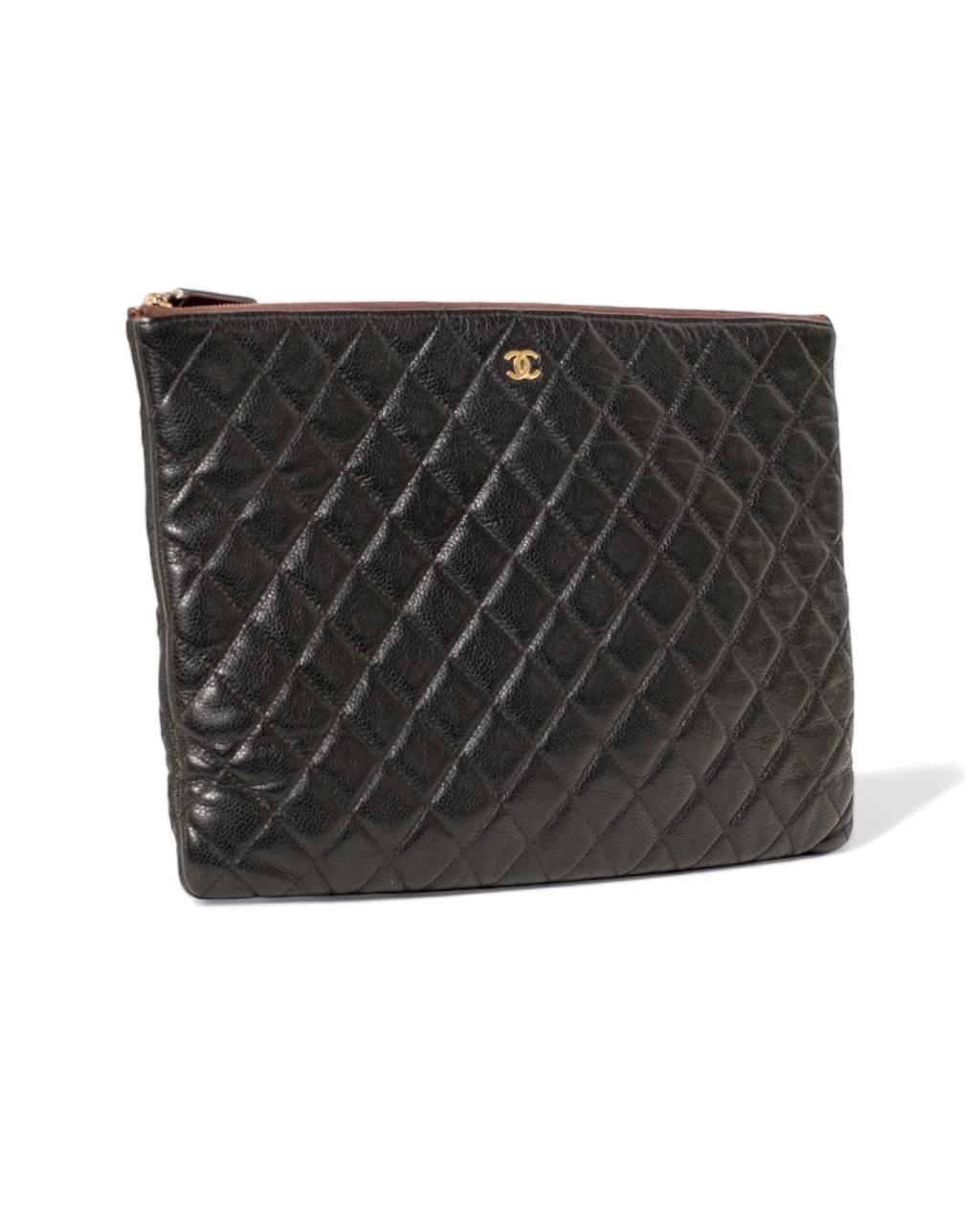 Clutch firmata Chanel, linea timeless, realizzata in pelle trapuntata caviar nera con hardware dorati. Dotata di una chiusura superiore a zip, internamente rivestita in nylon bordeaux, abbastanza presente. Anno di produzione 2013/2014, l'articolo si