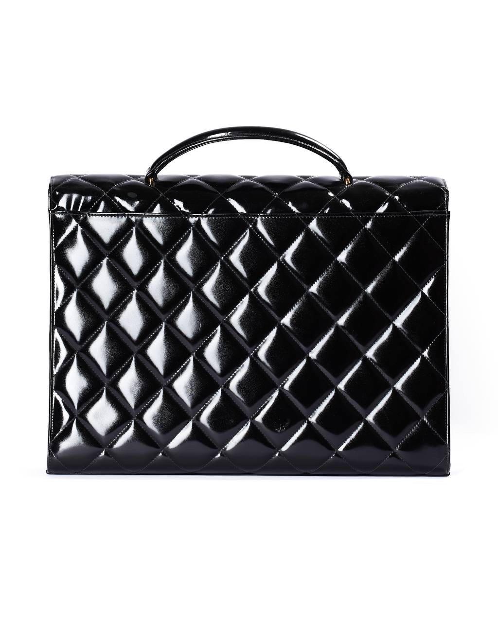 Valigetta firmata Chanel, linea Timeless, modello 24h, realizzata in pelle verniciata nera con hardware neri. Doté d'une patte frontale avec chiusura a girello con classico logo 