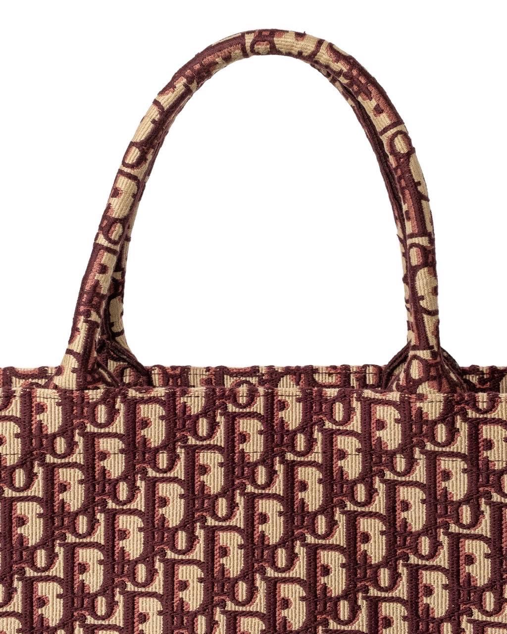 Borsa firmata Dior, Modello Book Tote, misura large, realizzata in tessuto nella fantasia oblique bordeaux. Dotata di un ampio scomparto centrale, internamente realizzata in tessuto tono su tono, molto capiente. Munita di due manici superiori, per