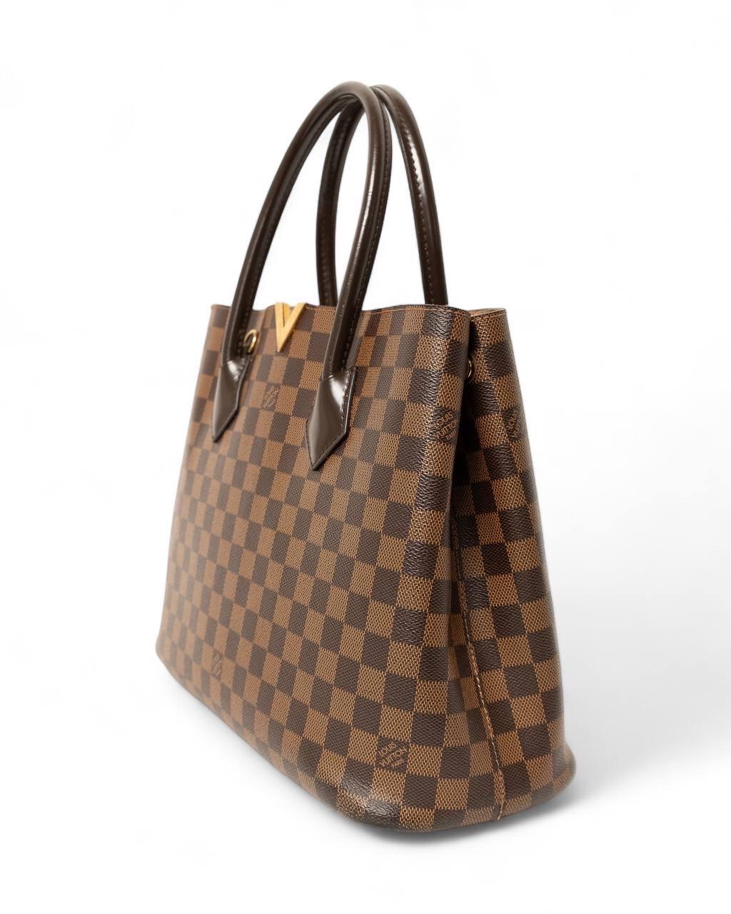Borsa firmata Louis Vuitton, modello Kensington, misura MM, realizzata in tela nella classica fantasia Damier Ebene con inserti in pelle e hardware dorati. Dotata di un ampio scomparto, internamente rivestita in tessuto scamosciato beige e comoda