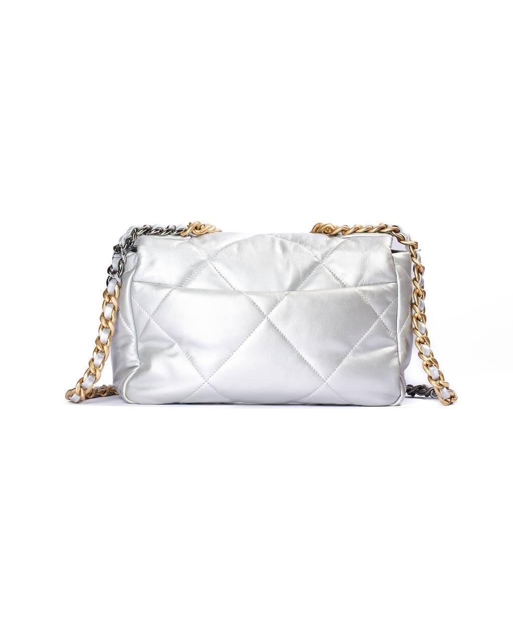 Borsa firmata Chanel, modello Flap, misura 19, realizzata in pelle liscia trapuntata nella colorazione silver con hardware oro/argento. Dotata di una patta frontale con chiusura a girello con classico logo “CC”, internamente rivestita in tela tono
