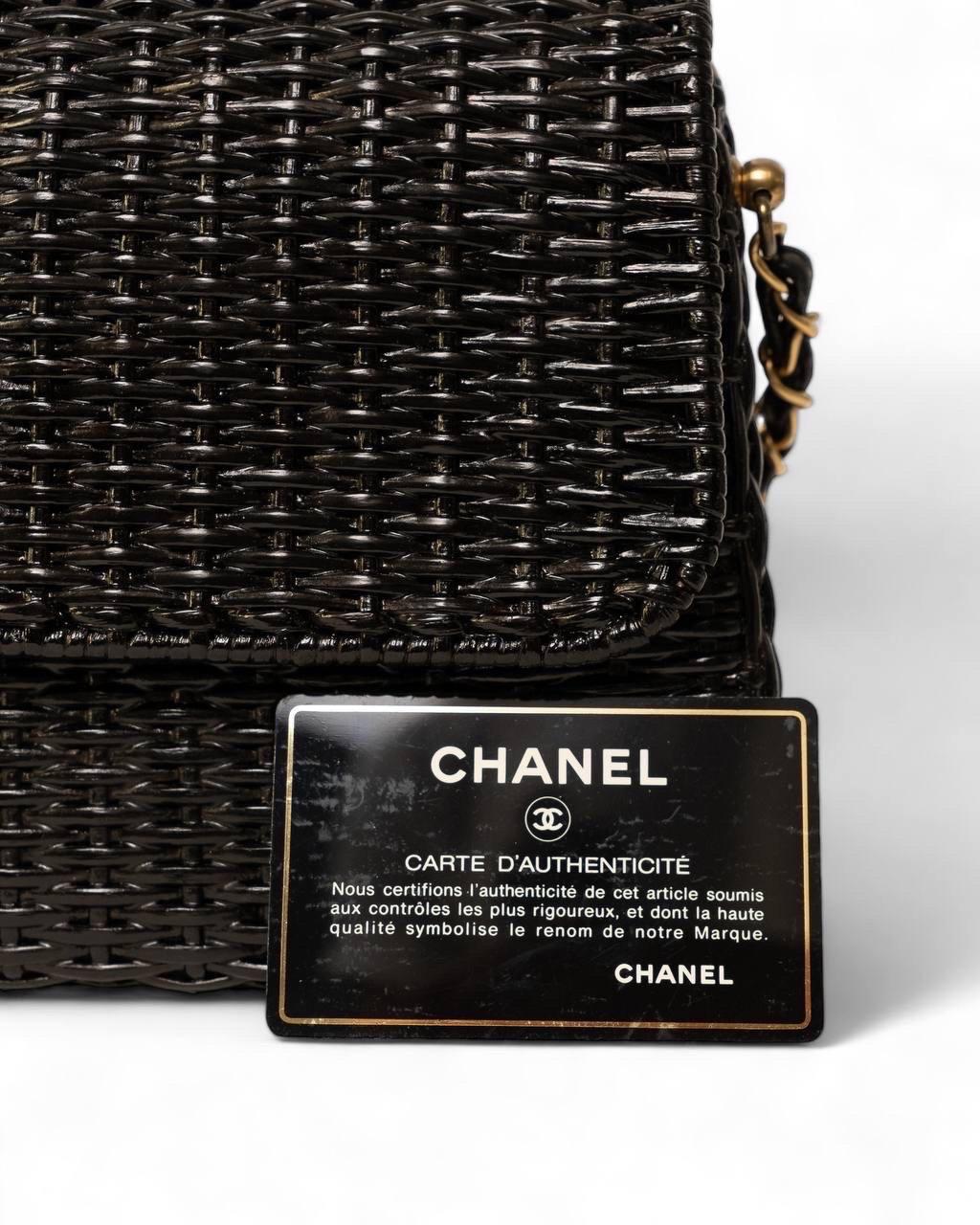 Borsa firmata Chanel, modello Flap, realizzata in Vimini nera con hardware dorati. Dotata di una patta frontale con chiusura a bottone calamitato, internamente rivestita in pelle liscia rossa, abbastanza capiente. Munita di una tracolla in catena e