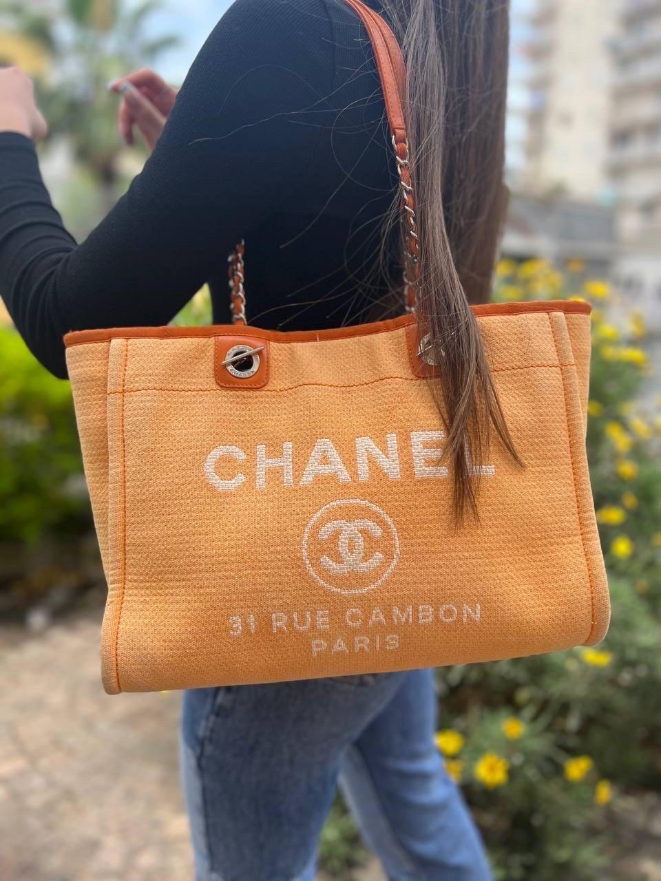 Borsa firmata Chanel, modello Deauville, realizzata in tela color arancio, con inserti in pelle e hardware argentati. Dotata di una chiusura centrale con bottone calamitato, internamente rivestita in tessuto arancio più scuro, molto capiente. Munita