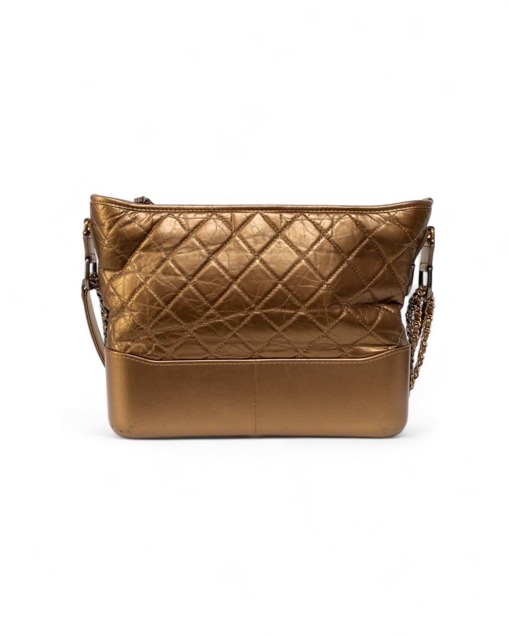Borsa firmata Chanel, modello Gabrielle, misura medium, realizzata in pelle dorata con hardware bicolor oro e argento. Doté d'un chiusura superiore a zip con Charm 