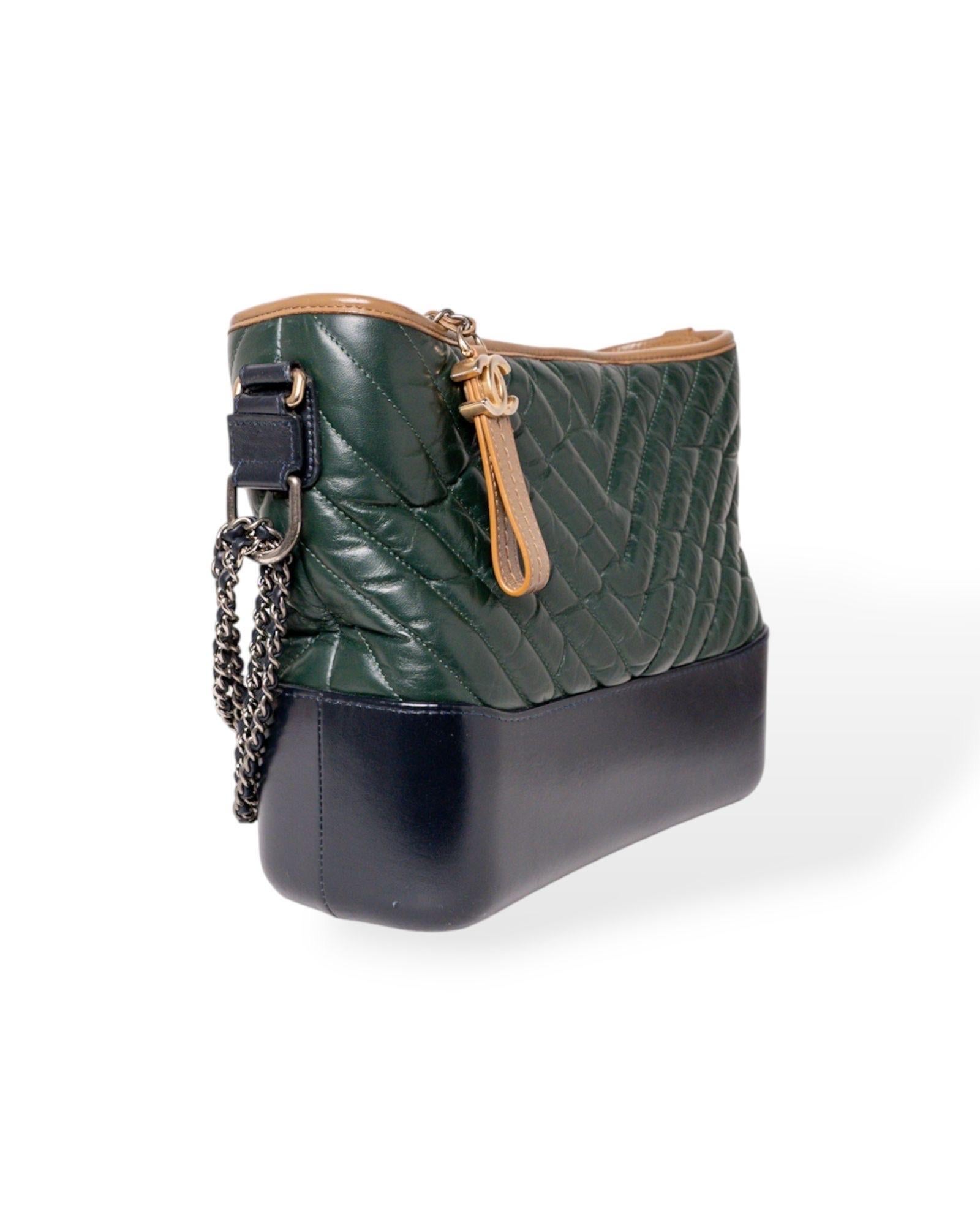 Borsa firmata Chanel, modello Gabrielle nella misura medium, realizzata in pregiata pelle nella colorazione verde e marrone con rifiniture blu e hardware bicolor in oro e argento. La chiusura superiore a zip è adornata da un charm “CC”, mentre