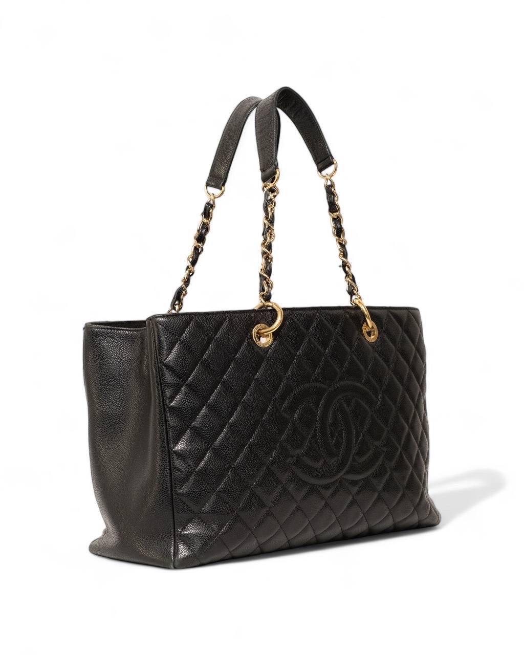 Borsa firmata Chanel, modello GST, realizzata in pelle caviar nera con hardware oro. Dotata di tre scomparti, uno dei quali con chiusura a zip. Munita di un doppio manico a spalla realizzato in pelle e catena. Internamente rivestita in tela tono su