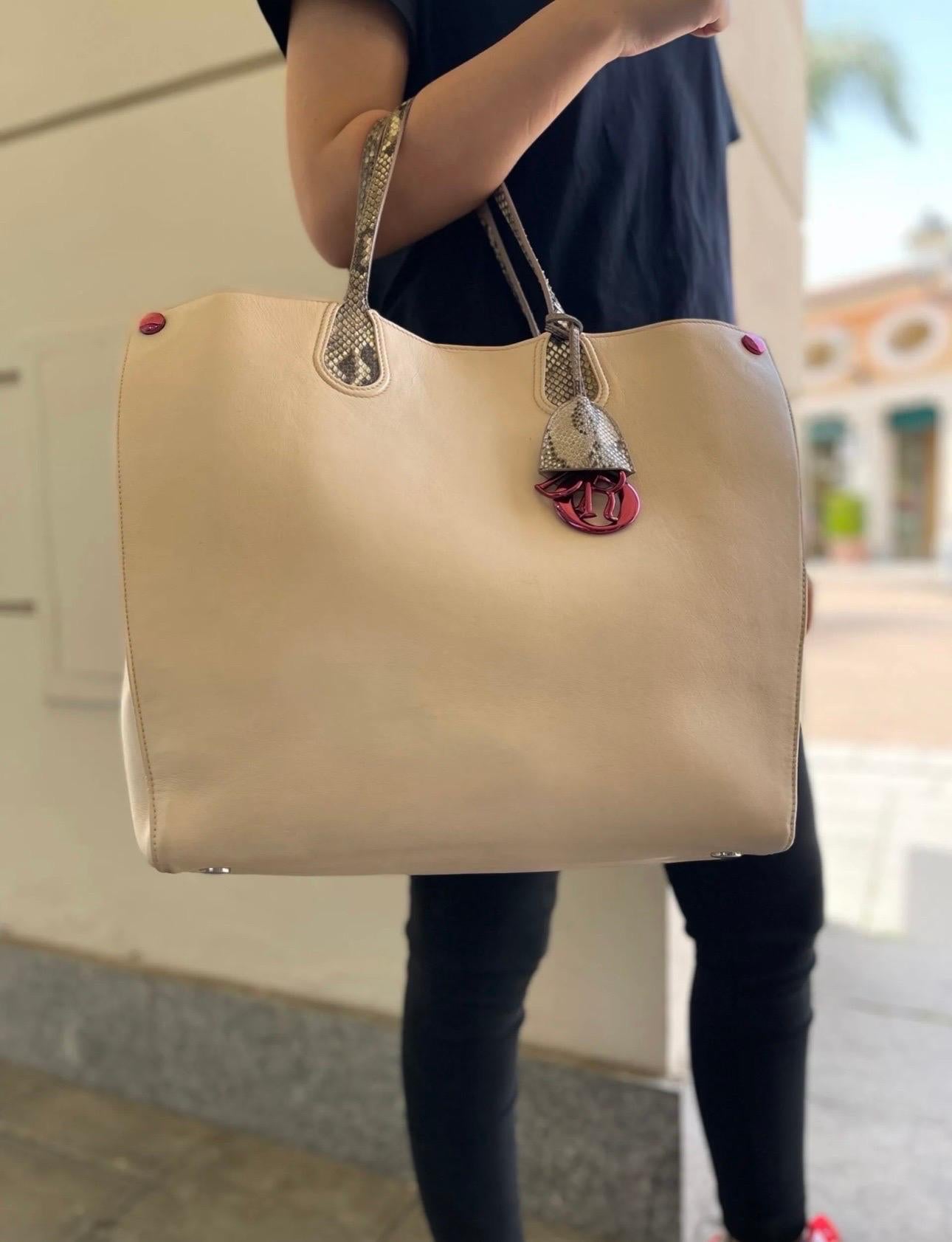 Borsa firmata Dior, modello shopper, realizzata in pelle cipria con manici pitonati. Dotata di una chiusura centrale con bottone calamitato, internamente rivestita in pelle cipria. Presenta in entrambe le estremità dei poussoir per restringere o