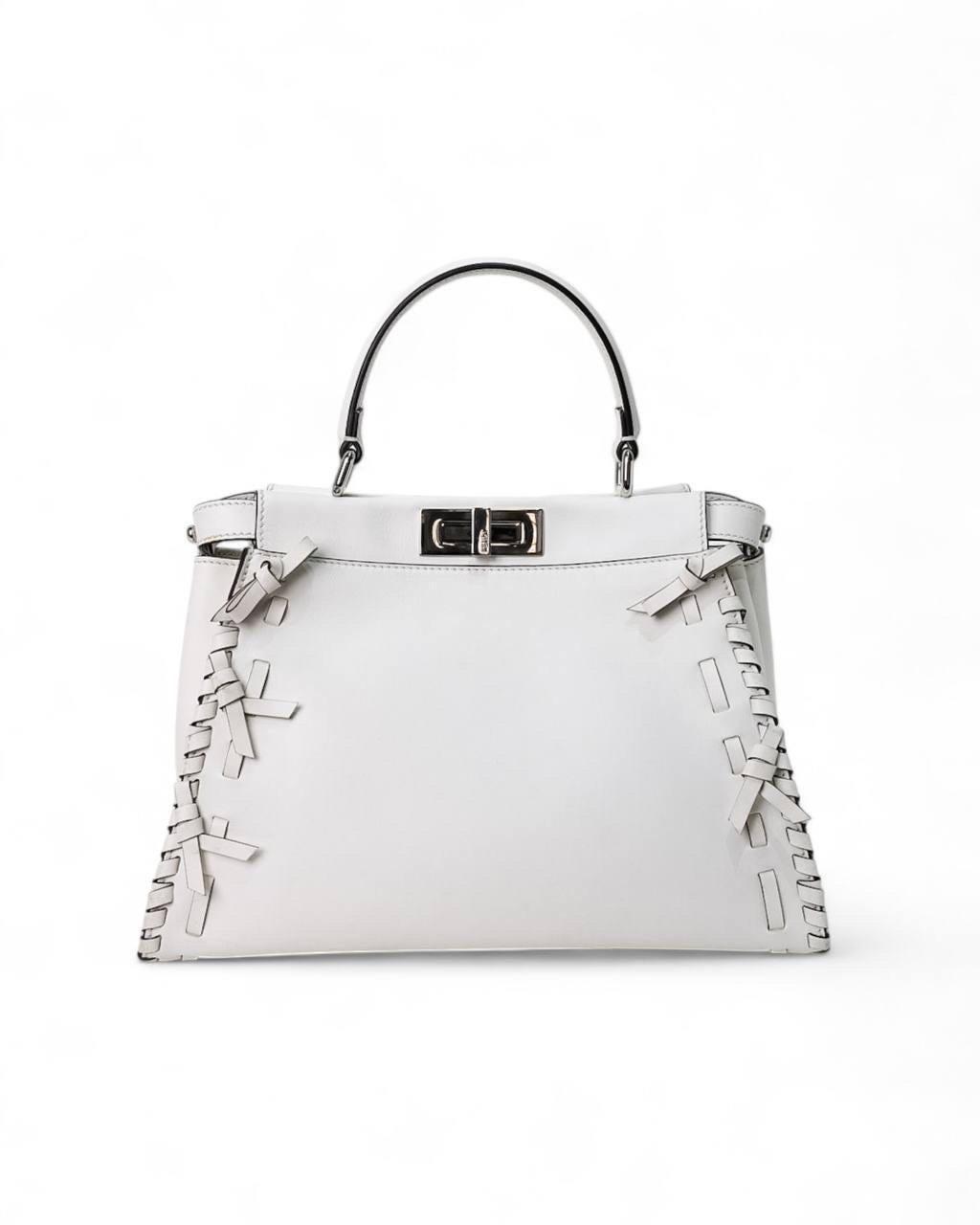 La borsa Fendi modello Peekaboo, nella misura media, è un autentico simbolo di eleganza e sofisticazione. Realizzata in morbida pelle bianca con hardware argentati che ne esaltano il design pulito e moderno. Dotata di doppia chiusura a girello