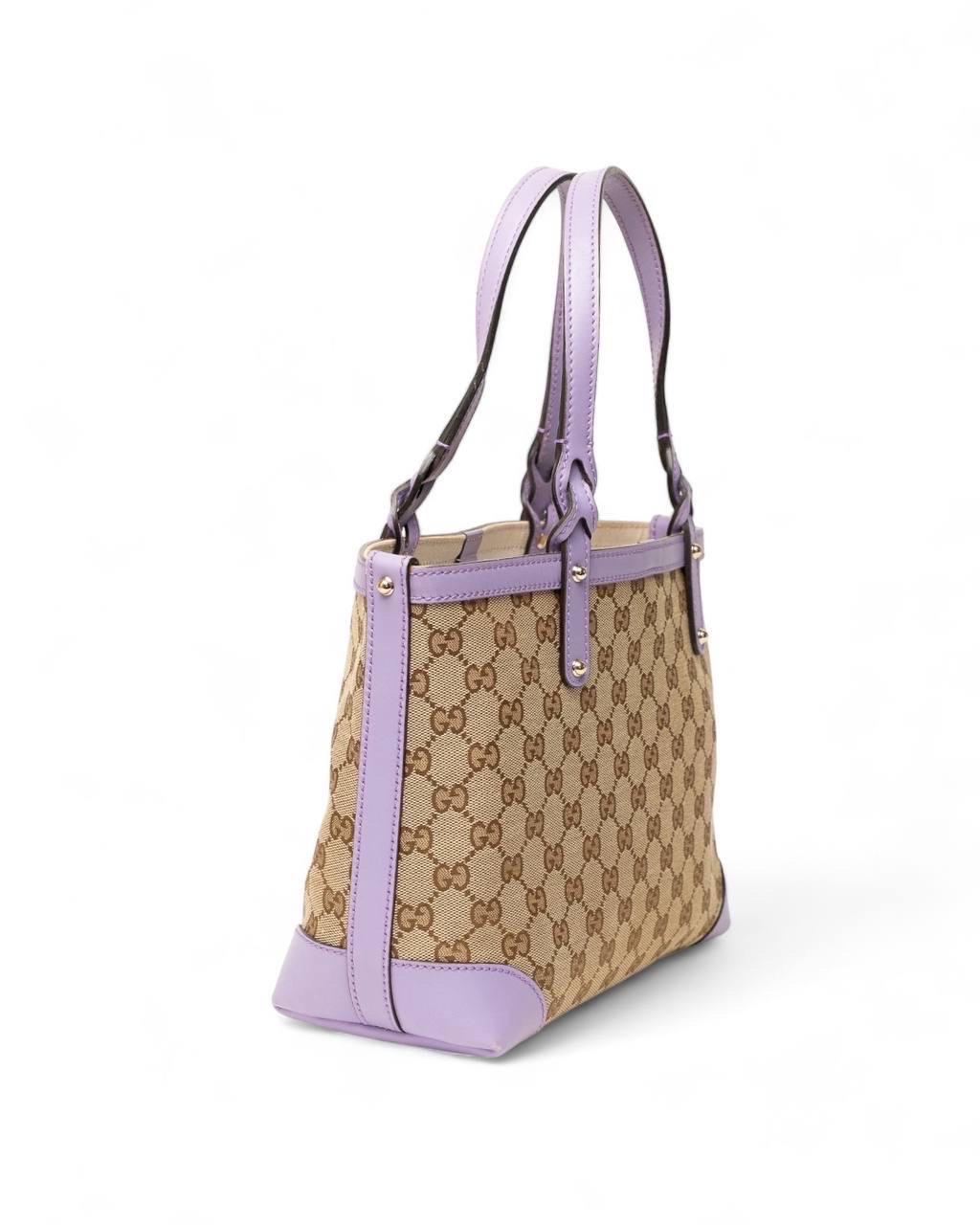 Borsa firmata Gucci, modello Shopper, misura Small, realizzata nella classica tela GG Supreme marrone con inserti in pelle lilla e hardware dorati. Doté d'une chiusura en terna a moschettone, internamente rivestita in tela beige, abbastanza