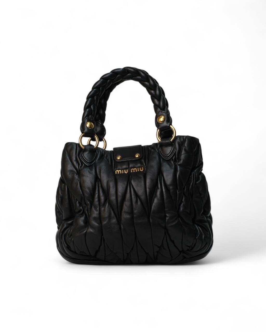 Borsa Firmata Miu Miu, modello Shopper, misura Small. realizzata in pelle Groffata nella colorazione nera con hardware dorati. Dotata di una patta con chiusura ad incastro, internamente rivestita di tela tono su tono con comoda tasca, abbastanza