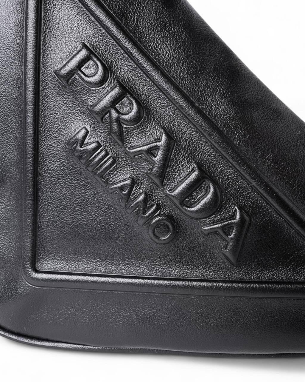 Borsa firmata Prada, modello Triangle, realizzata in pelle nera con hardware argentatI. Dotata di chiusura superiore a zip, l’interno è rivestito in tessuto logato tono su tono, offrendo ampio spazio per l’essenziale. La borsa è munita di un manico