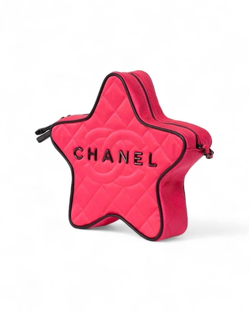 Borsa firmata Chanel, modello Star Bag, realizzata in raso trapuntato color fucsia con inserti in pelle nera e hardware neri. Dotata di una chiusura superiore a zip e di applicazione in metallo sulla parte frontale con logo ”CHANEL”. Munita di una