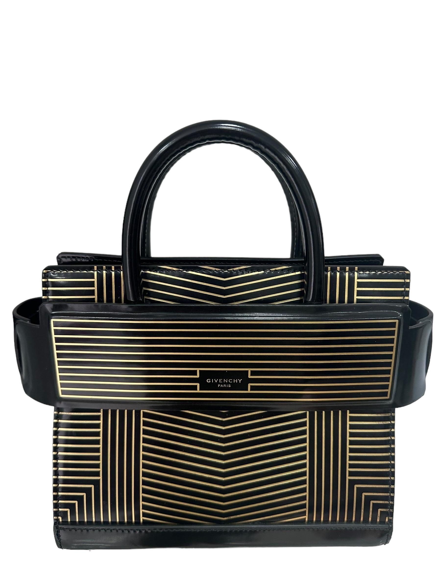Borsa firmata Givenchy, modello Horizon, realizzata in pelle verniciata nera con fantasia a righe oro con hardware dorati. Non è dotata di alcun tipo di chiusura, internamente rivestita in pelle nera, capiente per l’essenziale. Munita di doppio