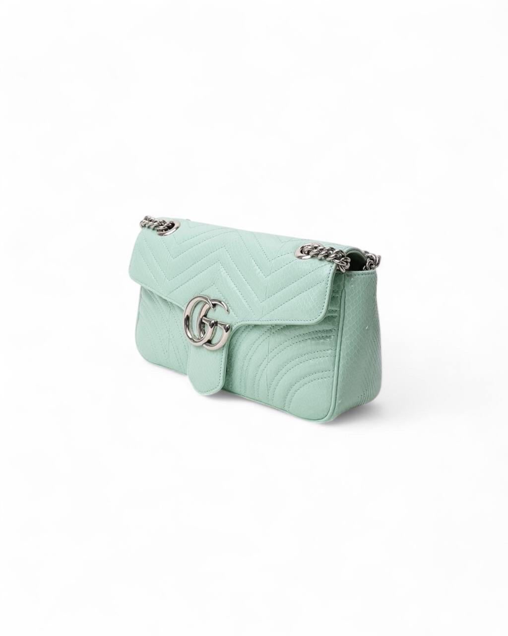 Borsa firmata Gucci, linea Marmont, realizzata in pregiata pelle nella raffinata colorazione tiffany con hardware argentati che conferiscono un tocco di lusso. Dotata di una patta frontale con chiusura ad incastro, mentre l’interno è rivestito in
