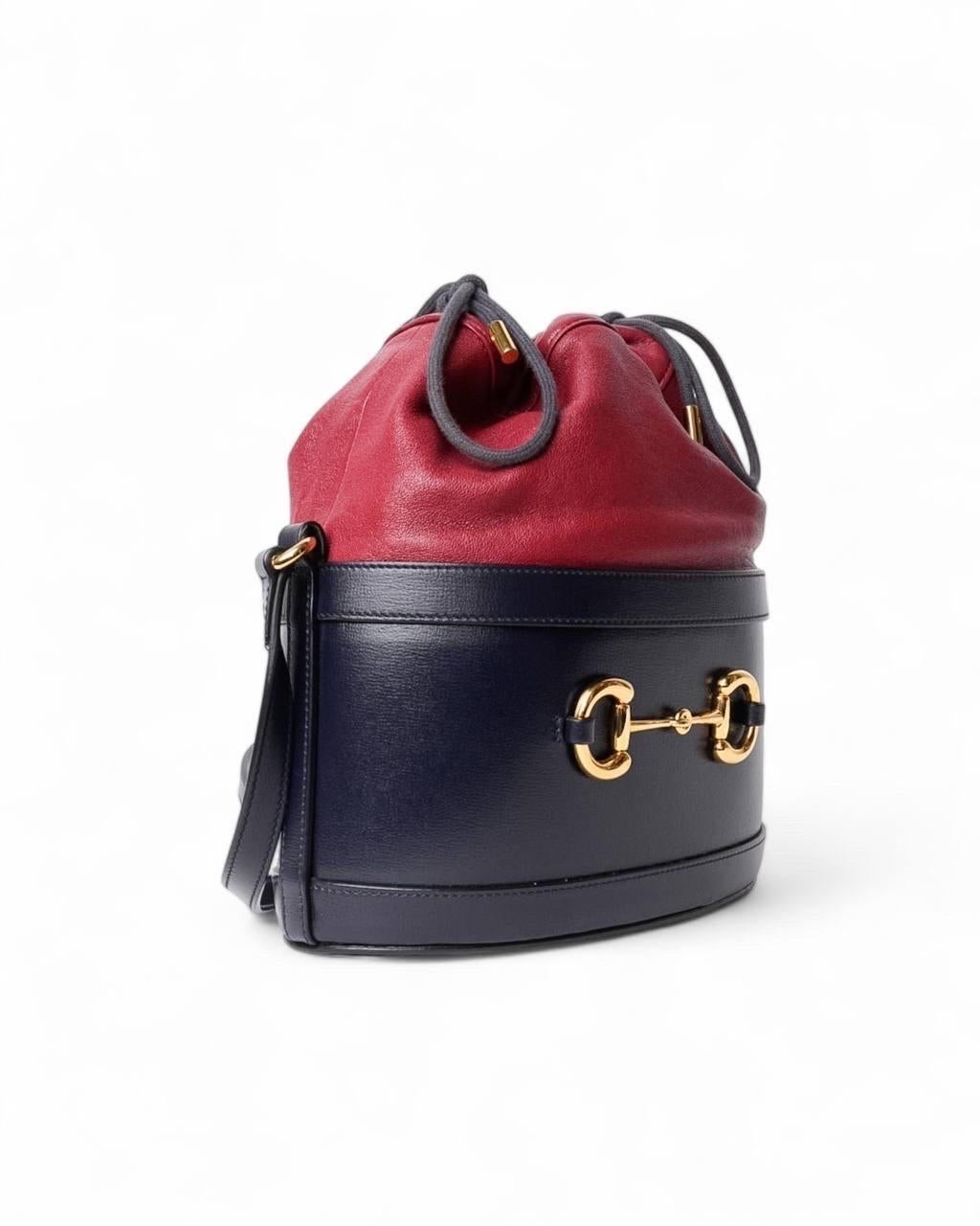 Borsa firmata Gucci, linea Horsebit 1955, modello secchiello, misura medium, realizzato in pelle nella colorazione blu e bordeaux con hardware dorati. Dotato di una chiusura superiore a coulisse, internamente rivestito in tessuto scamosciato beige