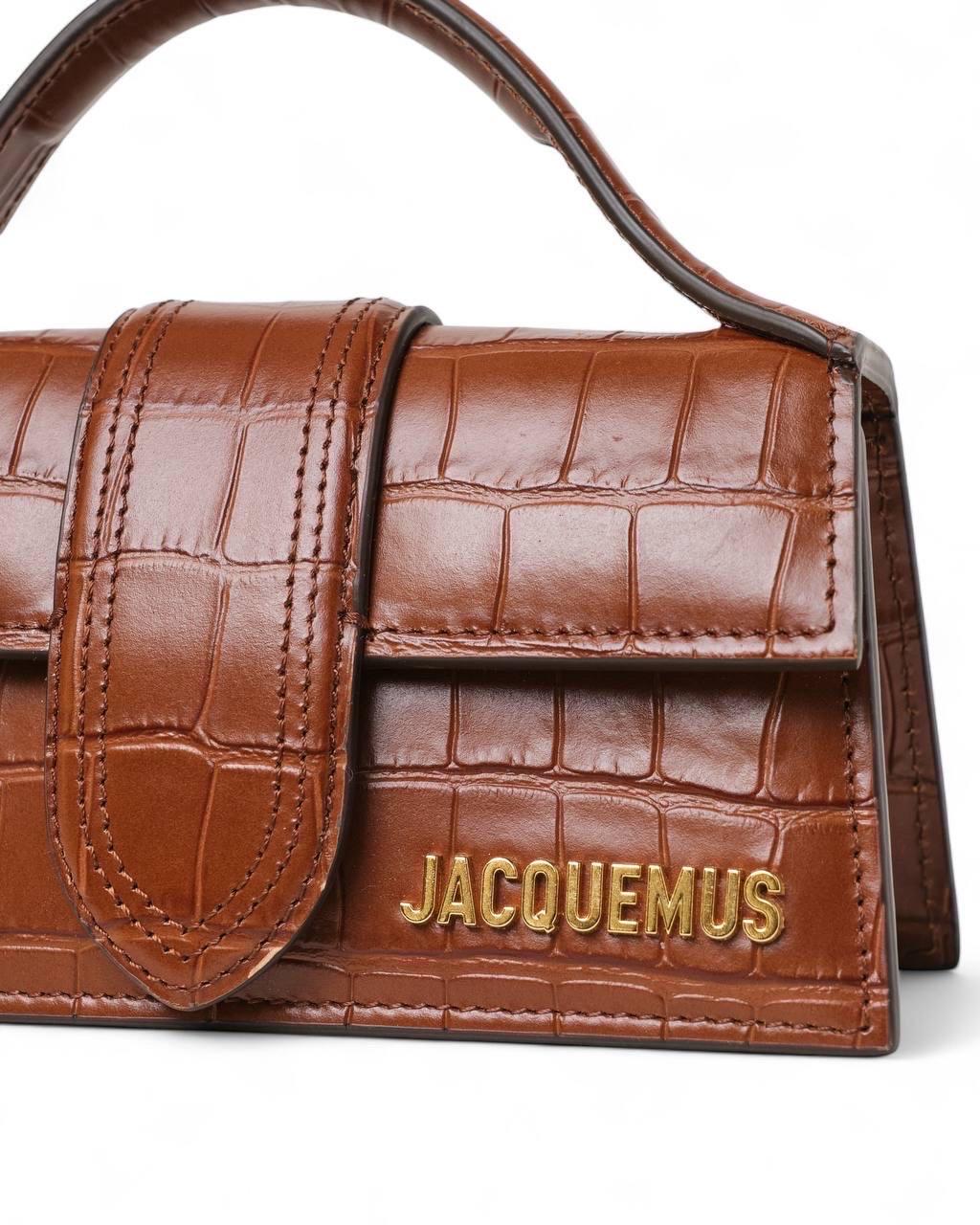 Borsa firmata Jacquemus, modello Le Bambino, misura mini, realizzata in pelle marrone nella fantasia cocco con hardware dorati. Dotata di una patta frontale con chiusura a bottone calamitato, internamente rivestita in tela beige, capiente per