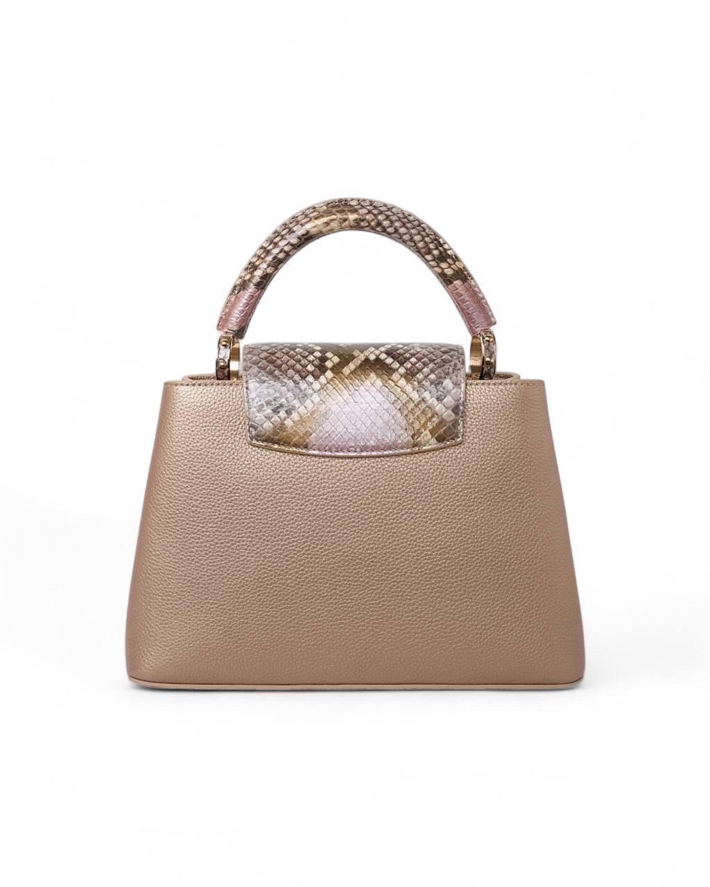 Borsa firmata Louis Vuitton, modello Capucines, misura BB, realizzata in pelle martellata di un elegante color oro con hardware dorati che ne esaltano il design sofisticato. Dotata di una patta centrale che garantisce una chiusura sicura,