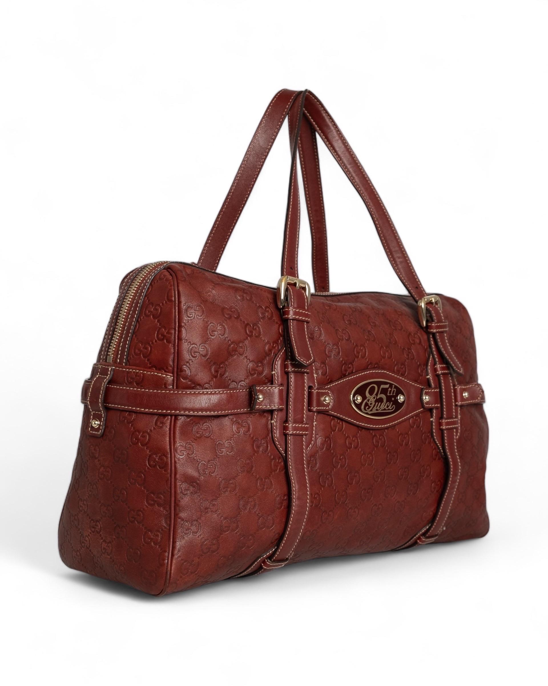 Borsa firmata Gucci, modello Boston 85th Anniversary Limited Edition, realizzata in pelle rossa e hardware oro. Presenta su tutta la superficie la classica trama GG supreme impressa su pelle, placchetta in metallo oro e bordeaux con la dicitura