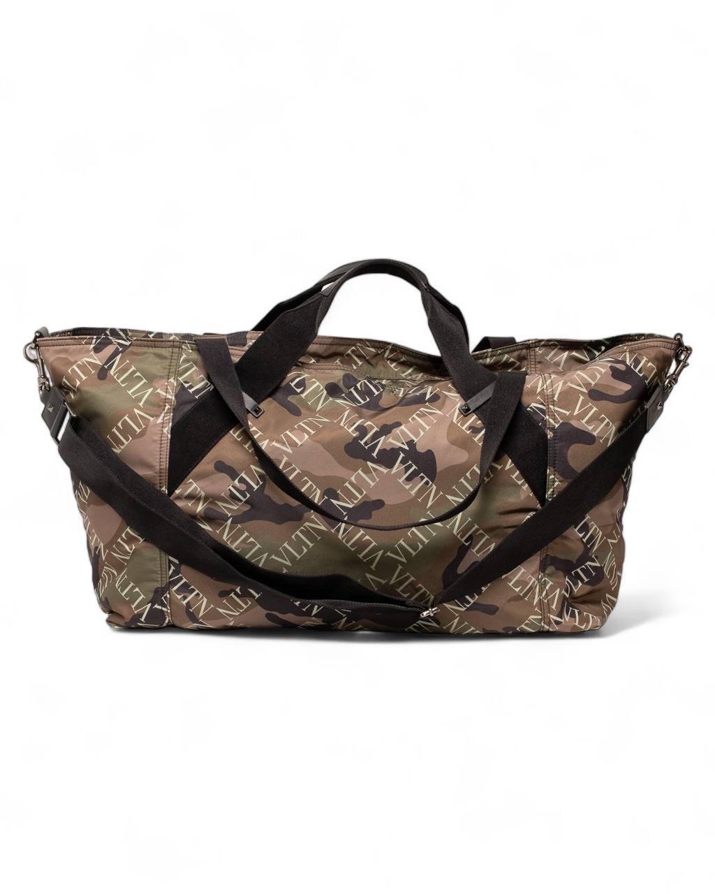 Borsone da viaggio firmato Valentino, realizzato in nylon verde nella fantasia Camouflage con inserti in tessuto nero e hardware argentati. Dotato di una chiusura superiore a zip, internamente rivestito in nylon nero, molto capiente. Munito di