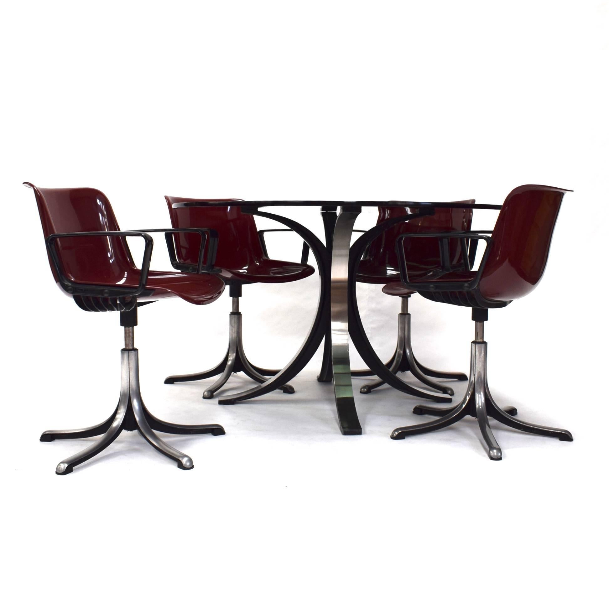 T69 dining set by Osvaldo Borsani for TECNO. The table and chairs are made of brushed aluminium. The chairs (swivel) have five aluminum feet, plastic seat shells in a Bordeaux red colour and black plastic armrests. The glass table is made of thick