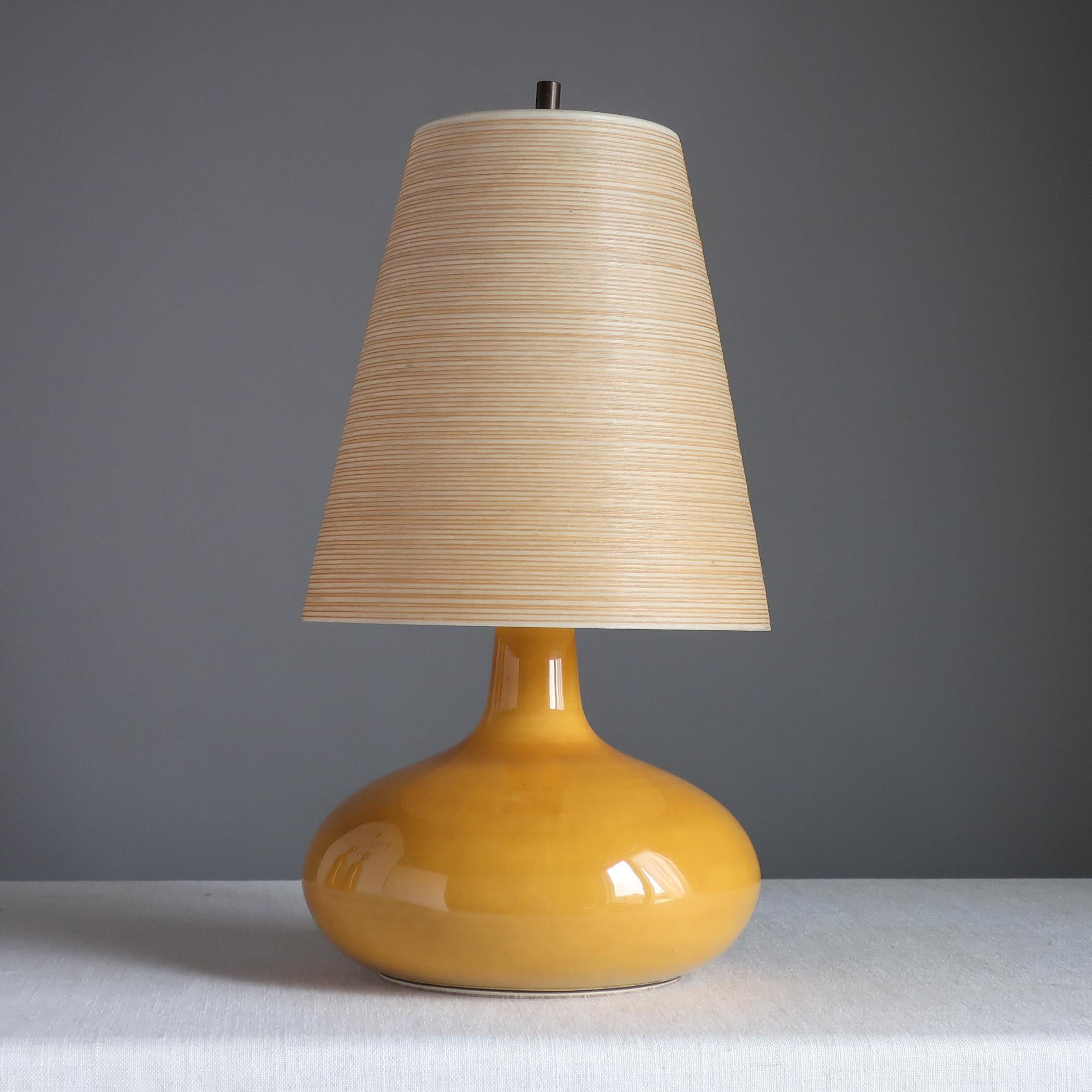 Midcentury ceramic table lamp designed by Canadian/Danish couple Lotte and Gunnar Bostlund. The simple stoneware body has a mustard-yellow glaze. Retains its original twine-wrapped fiberglass shade. Bostlund label around cord hole at