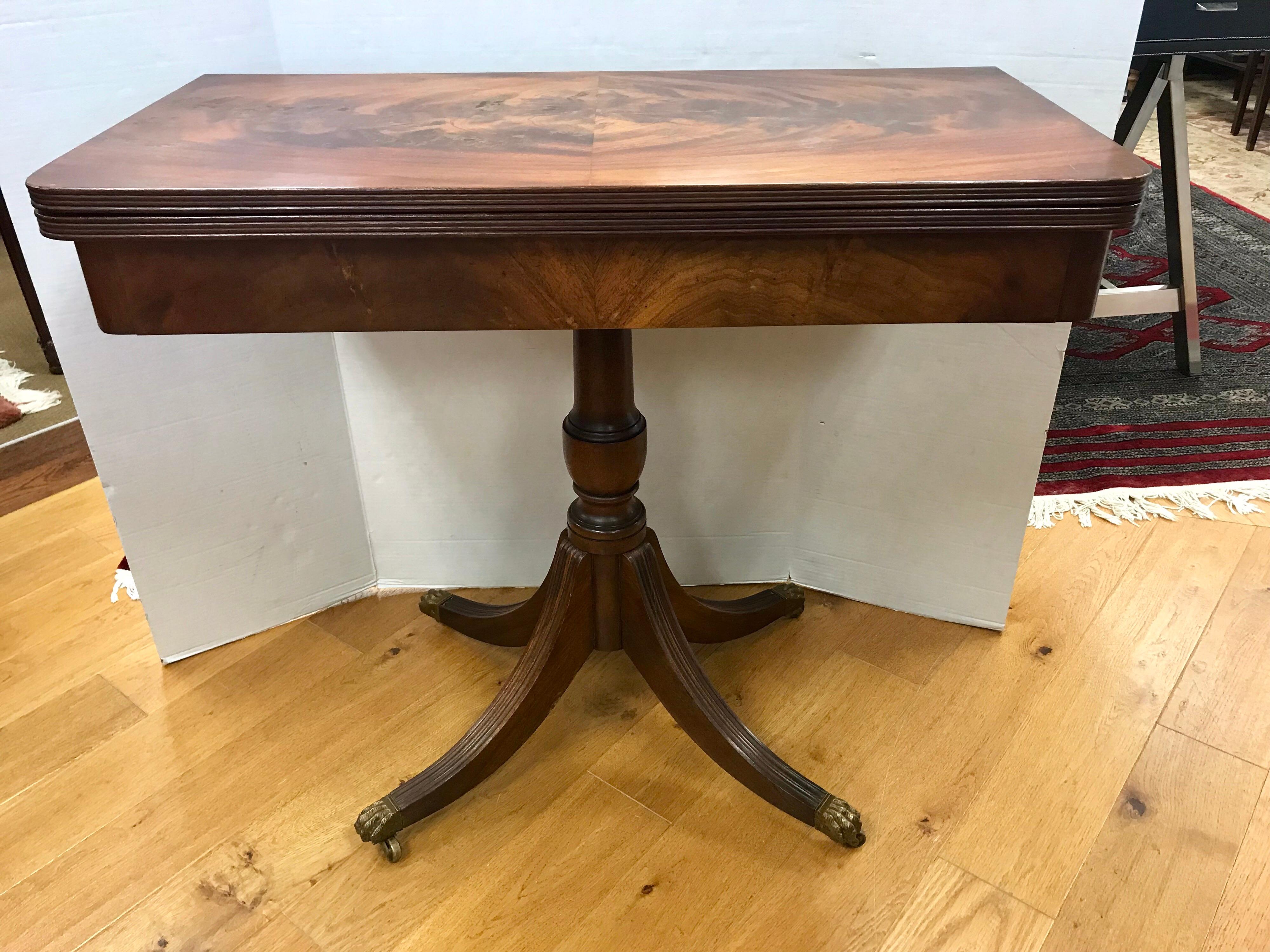 An exceptionally handsome and very well crafted classic Federal game table in premium flame mahogany with turned and finely carved pedestal base, with brass saber feet atop caster wheels. Top opens and pivots to a square, circa mid-19th Century,