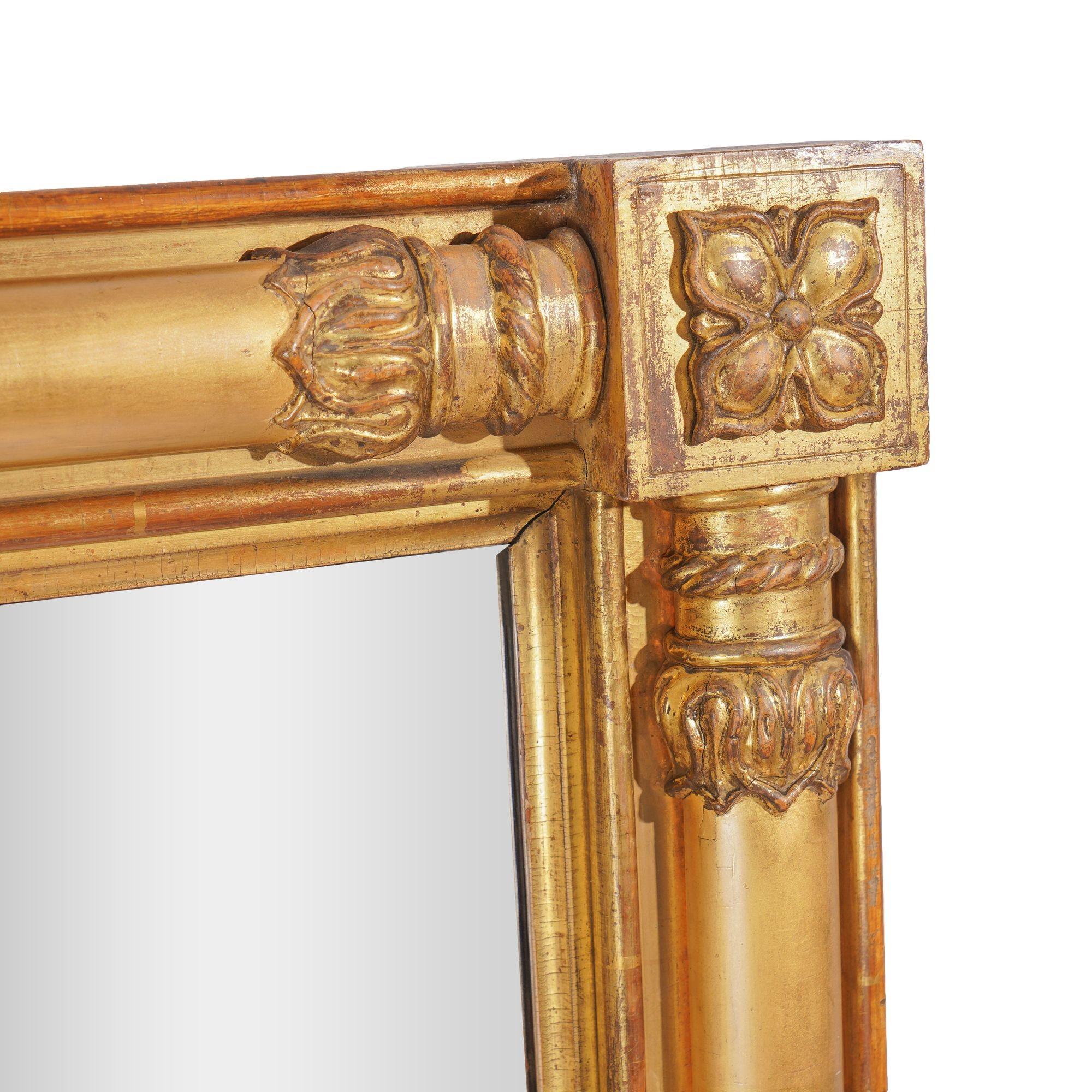 American Neoclassic rectangular frame pier mirror of turned half columns with carved lamb’s tongue terminals and blocked corners encasing a four petal floret. The vertical half columns are separated by reeded half turnings which frame the center of