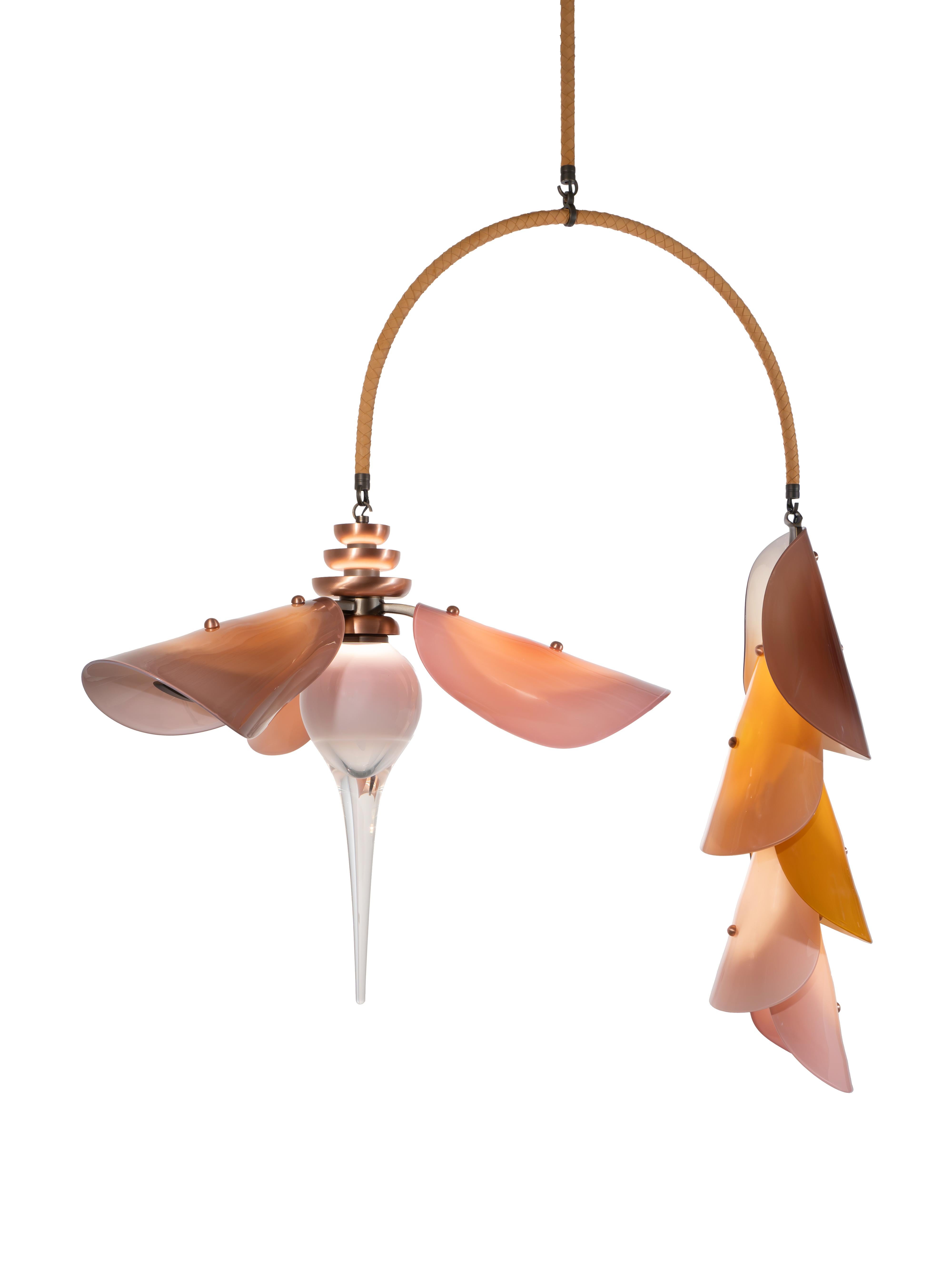 Le lustre Botanica associe une fleur à l'échelle spectaculaire à une chaîne de feuilles de verre imbriquées, suspendues à un arc unique revêtu de cuir tissé à la main. Inspirée par les fleurs de bananier et les célèbres jardins botaniques de