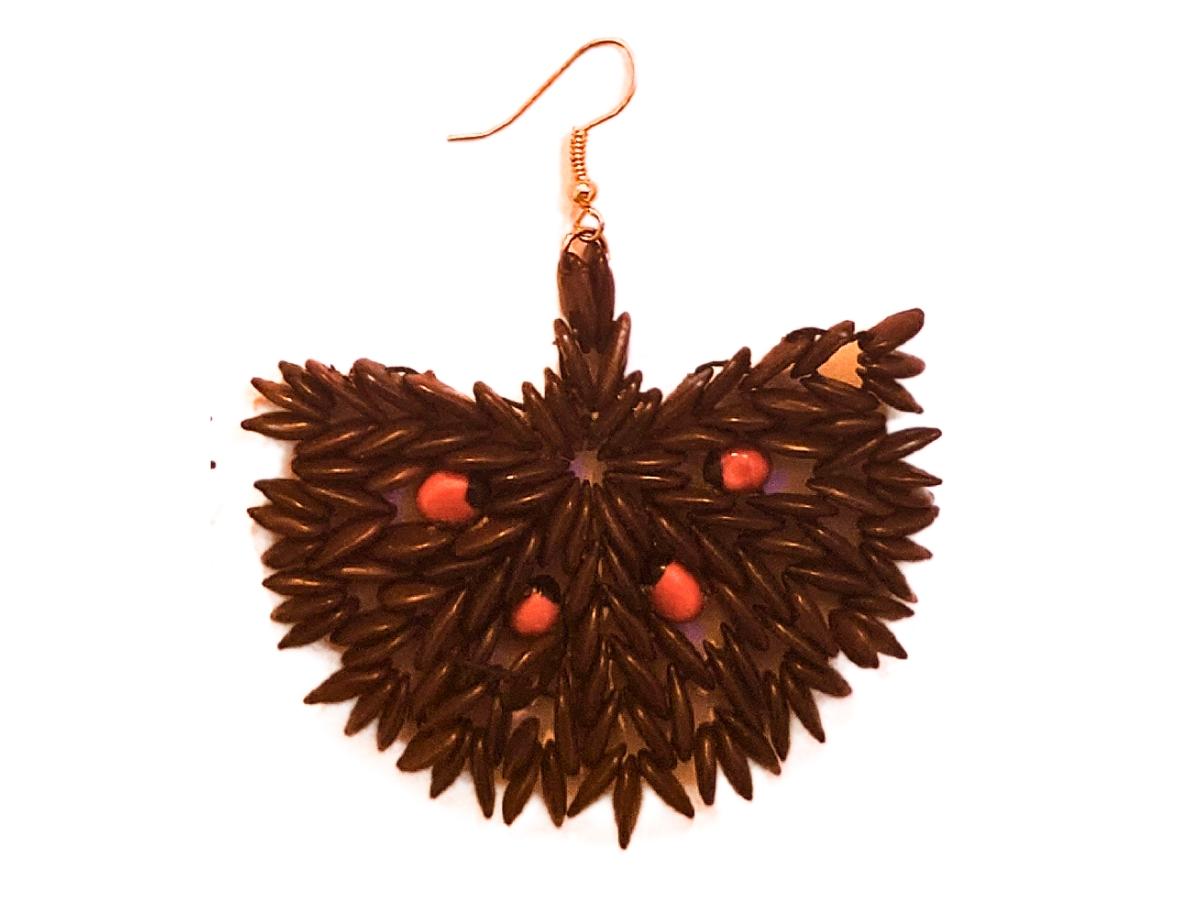 The Ember Blossom Earrings evoke the beauty of nature’s vibrant yet grounded hues, combining deep brown wild tamarind seeds with the fiery accent of red jumbie beads. The intricate arrangement of the tamarind seeds forms a fan-like bloom, while the