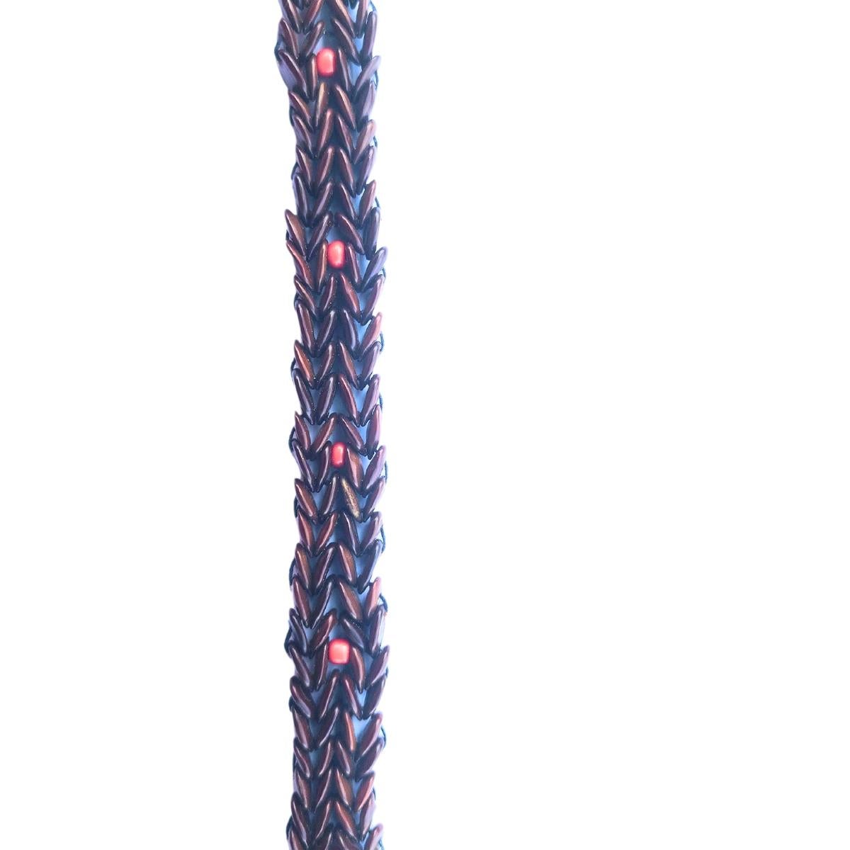 La Pulsera Sendero de Ascuas es una llamativa creación que combina la riqueza terrosa de las semillas de tamarindo silvestre marrón con la llamativa vitalidad de las cuentas de jumbie rojo. Estas cuentas rojas están sutilmente intercaladas a lo