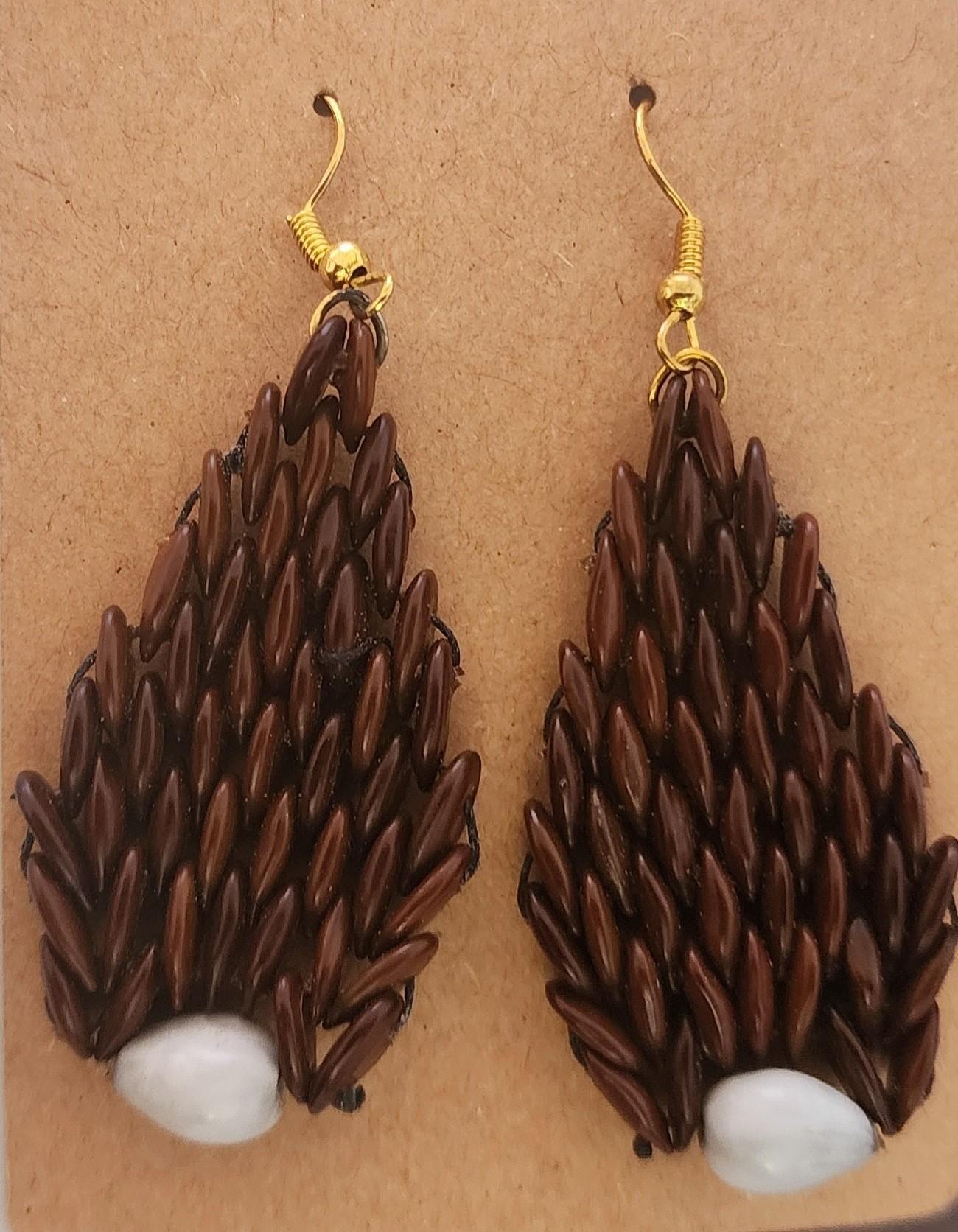 The Tears of the Earth Earrings are a stunning representation of nature’s textures and colors, featuring a cascade of deep brown wild tamarind seeds accented by the gentle shine of a single Job’s Tear seed at the base of each earring. The organic