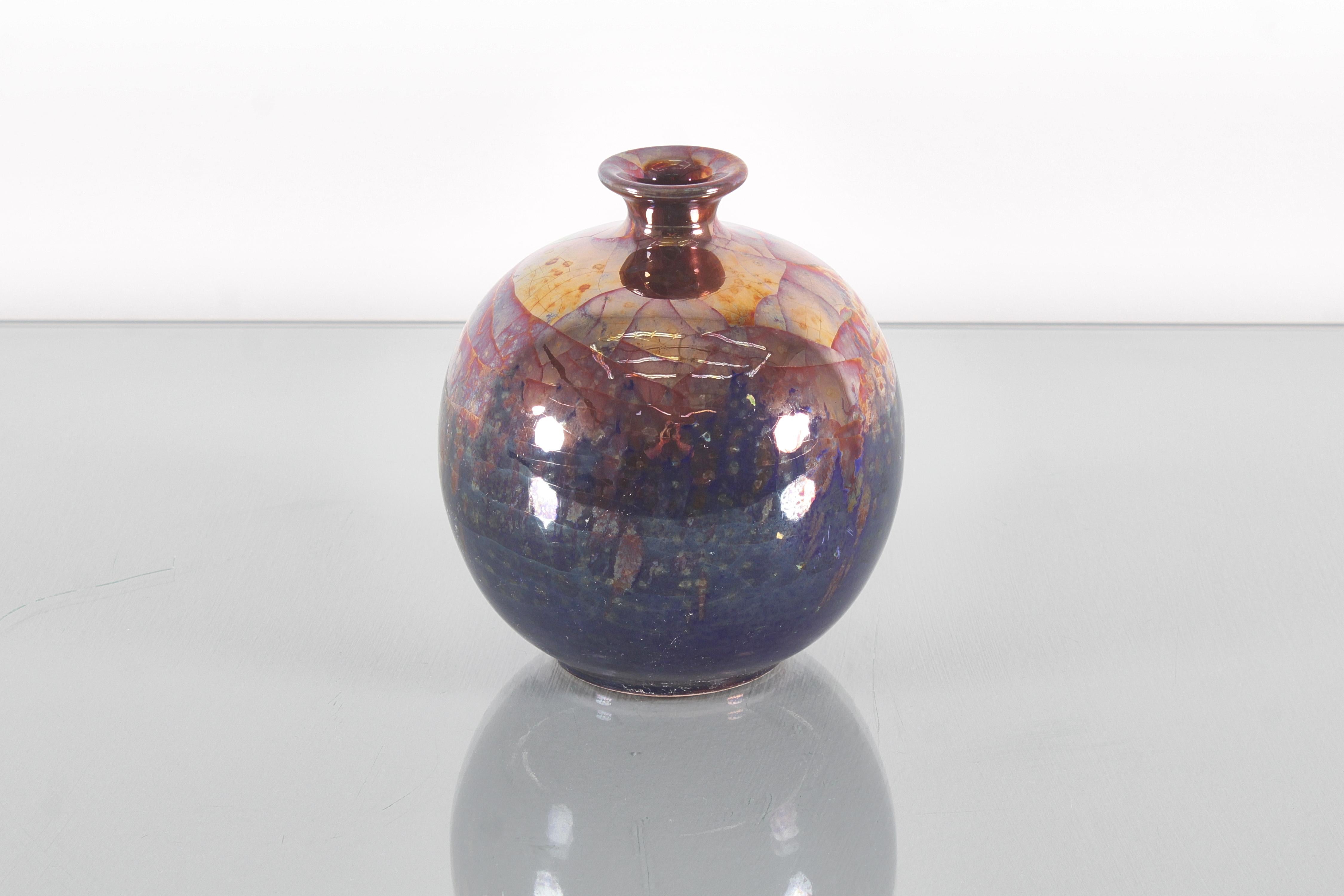 Sphere vase in polychrome glazed ceramic in dark shades with irregular copper plating and a crackle effect. Signed on the bottom 
