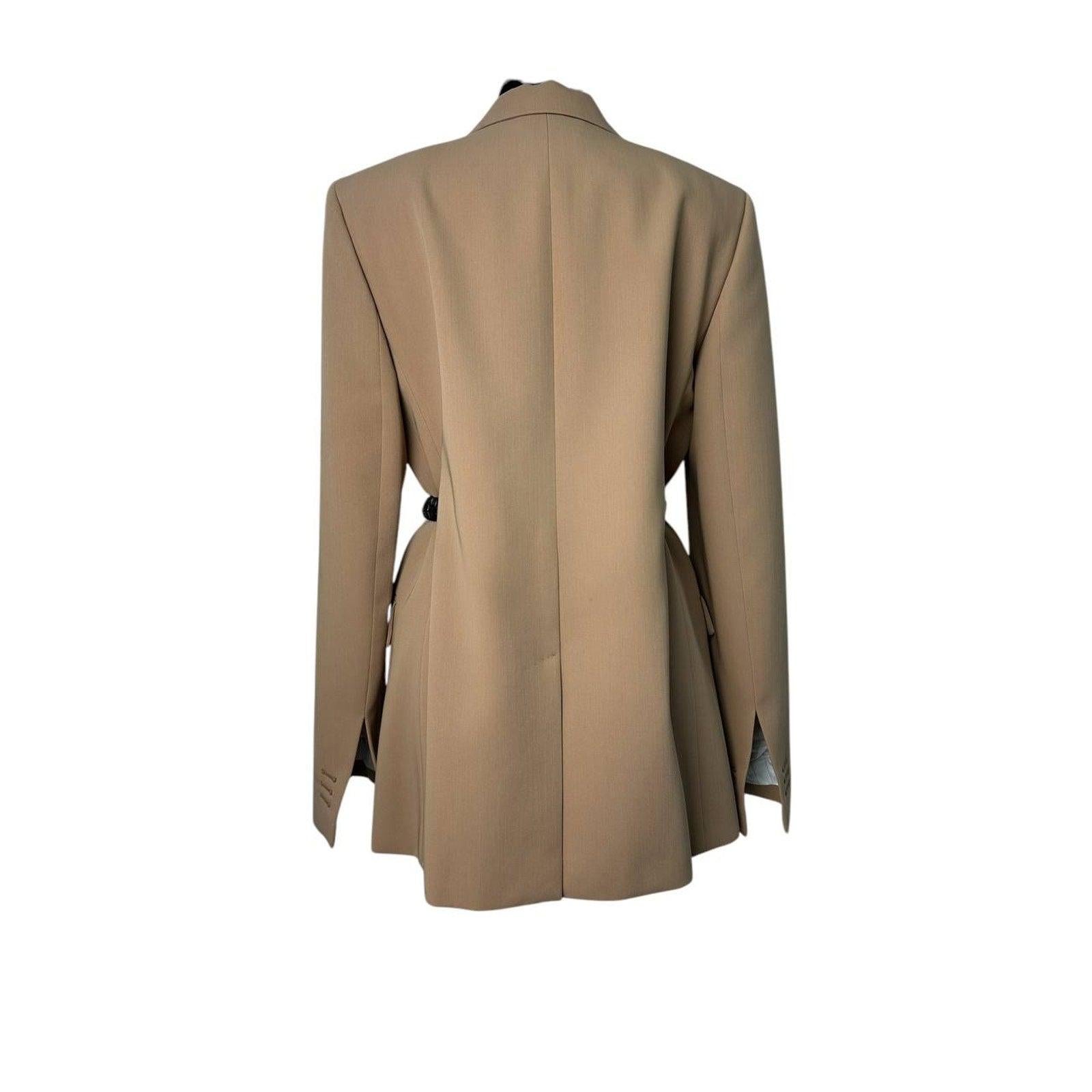 
Dieser beigefarbene Longline-Blazer definiert die moderne Schneiderkunst mit einer raffinierten Silhouette und kreativen Akzenten neu. Ein klassisches Revers und ein Zwei-Knopf-Verschluss werden durch dekorative Kordeln auf der Rückseite subtil